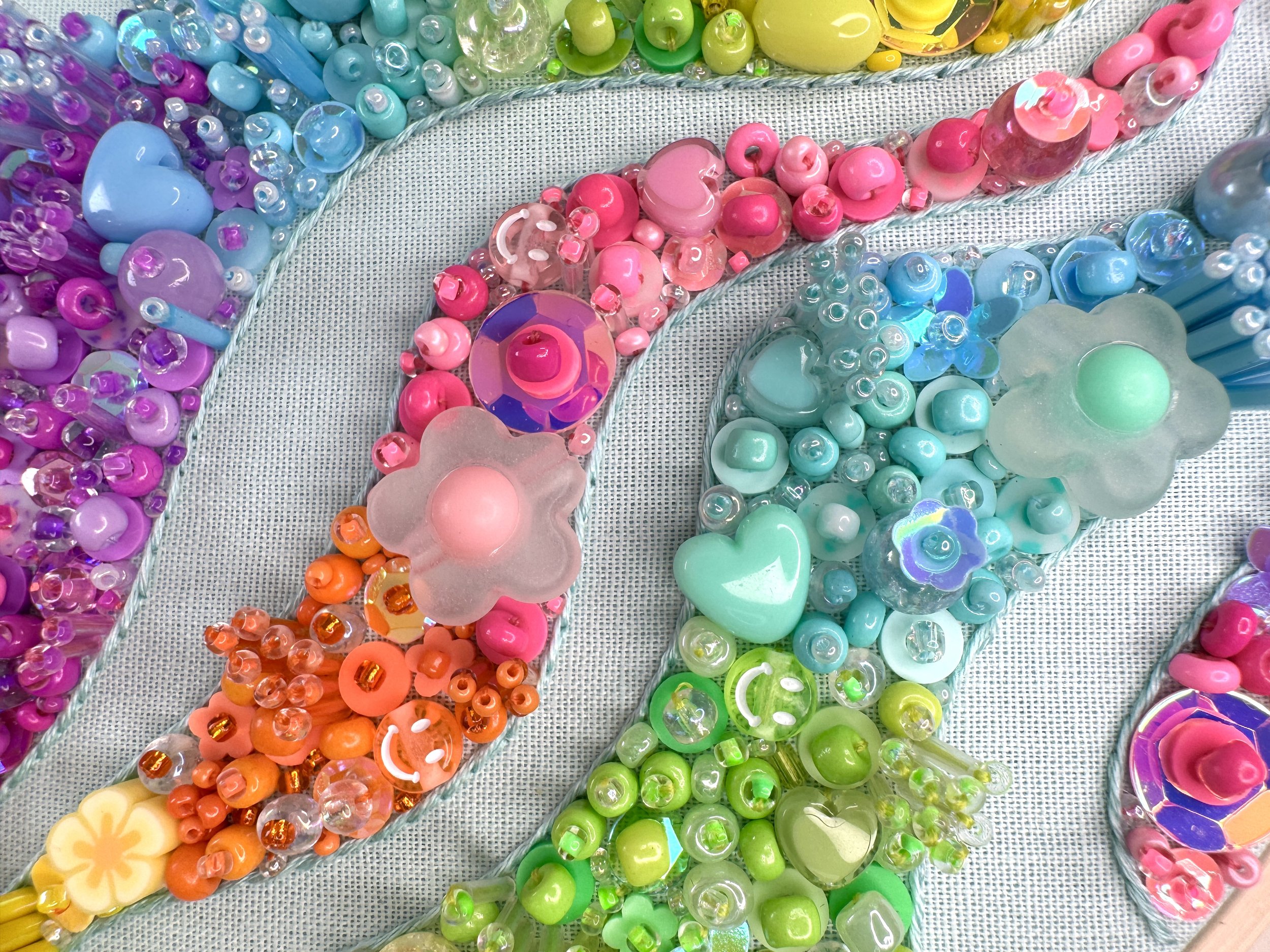 Close-up of colorful glass art beads arranged in circular patterns on a textured surface.