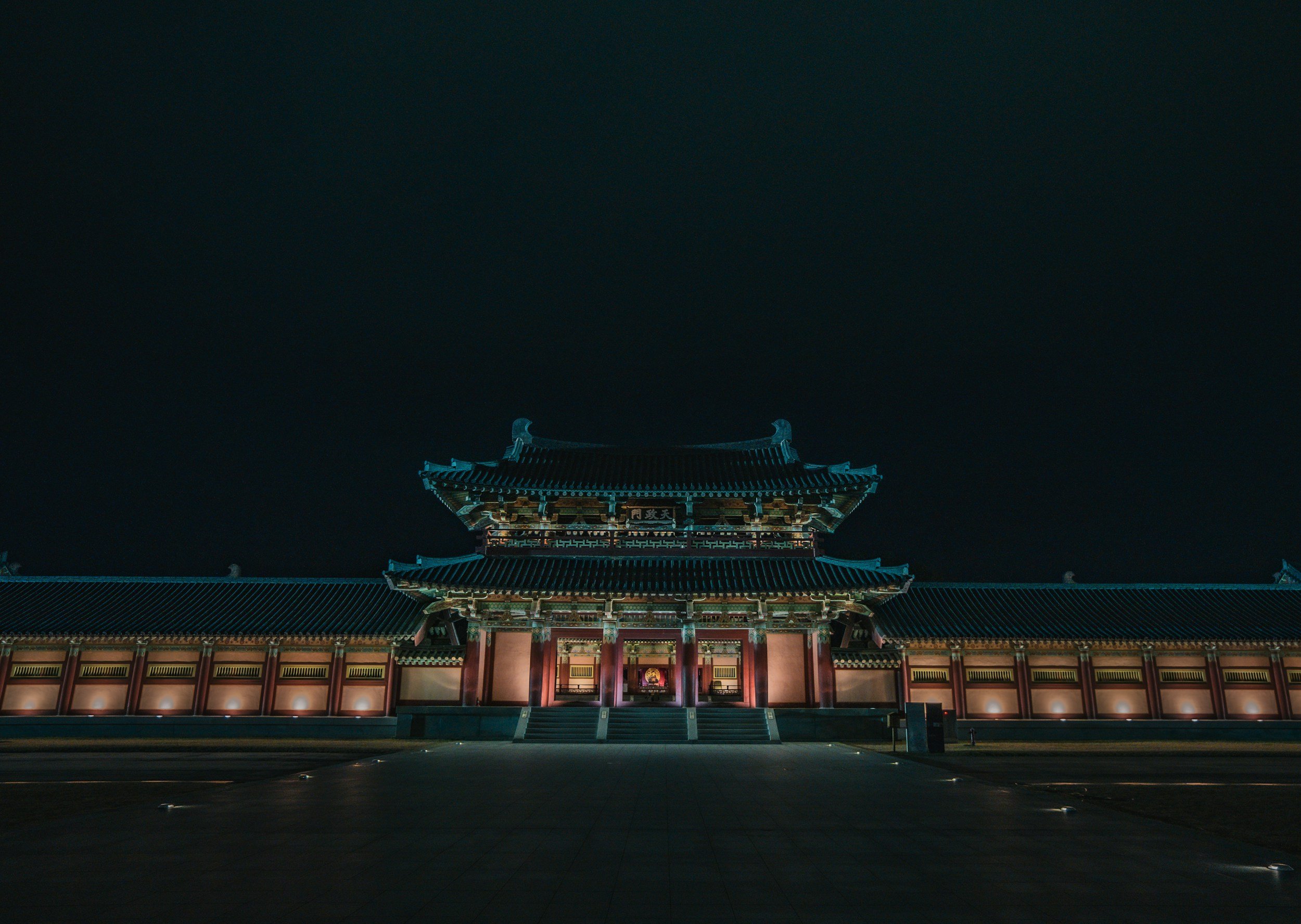Edificio tradizionale cinese illuminato di notte, con un cielo scuro sullo sfondo.