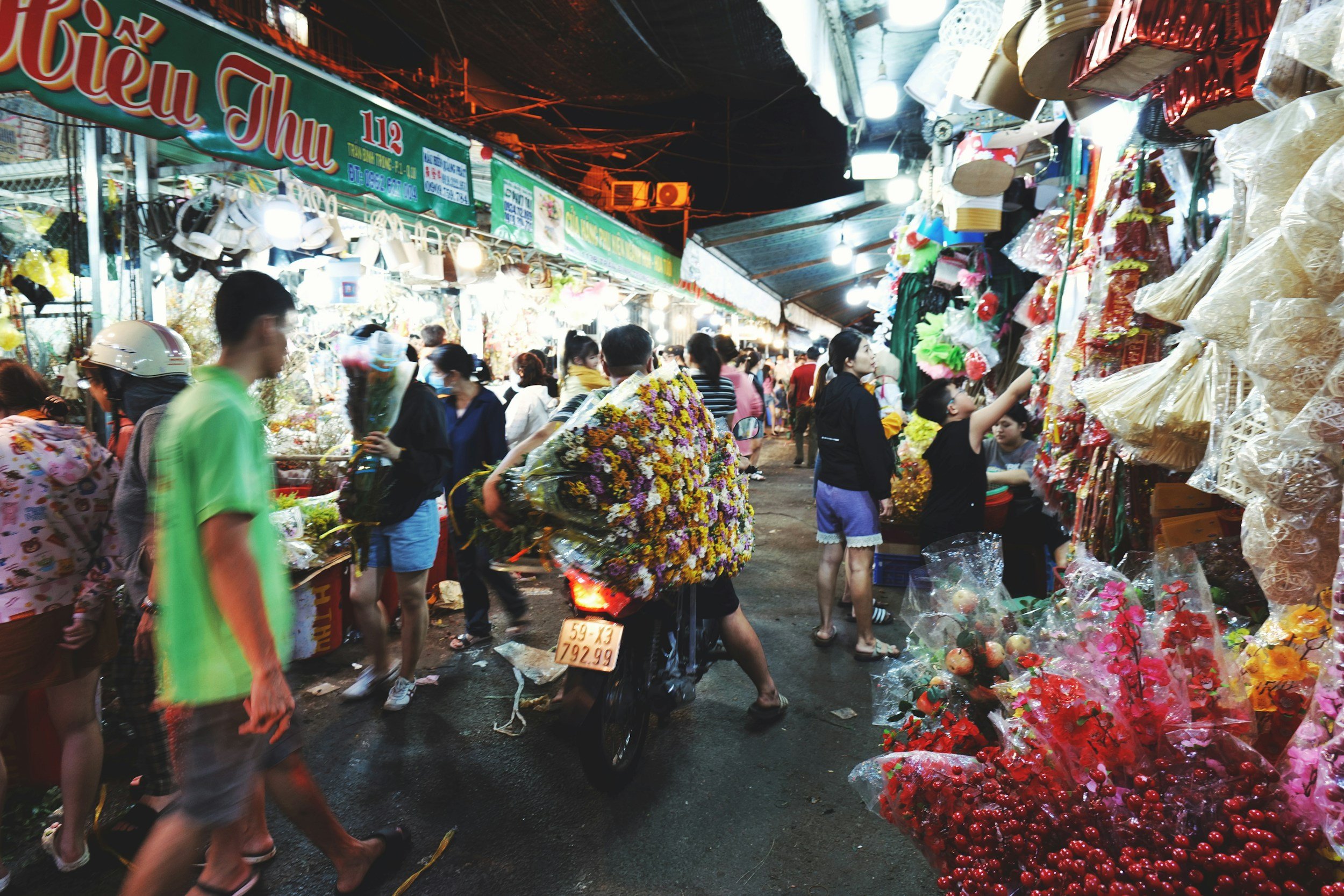 mercato notturno con molte persone e bancarelle di fiori e oggetti colorati, colorazione vivace con luci artificiali in Thailandia