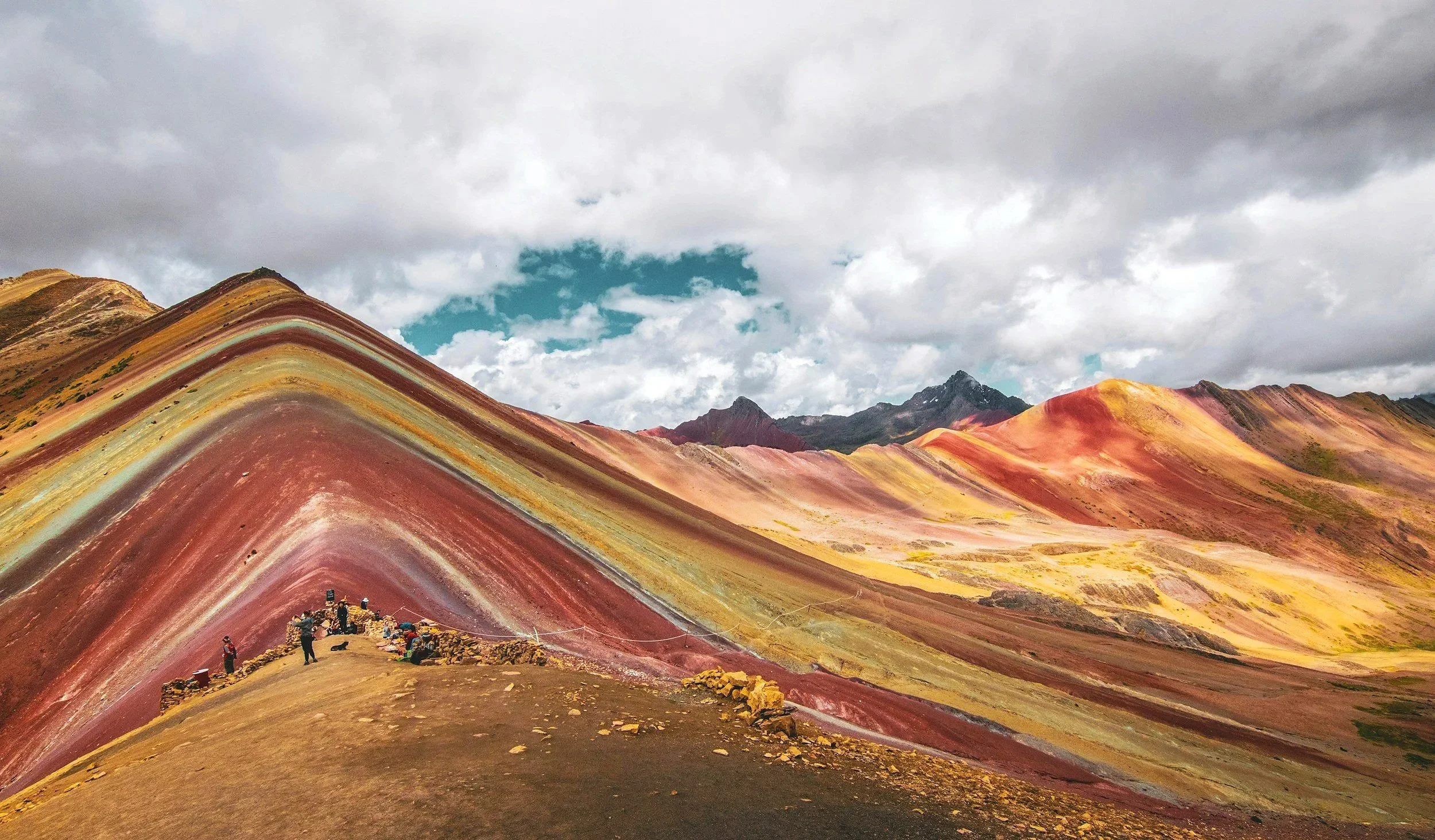 Paesaggio montano con colline colorate e cielo nuvoloso. Perù