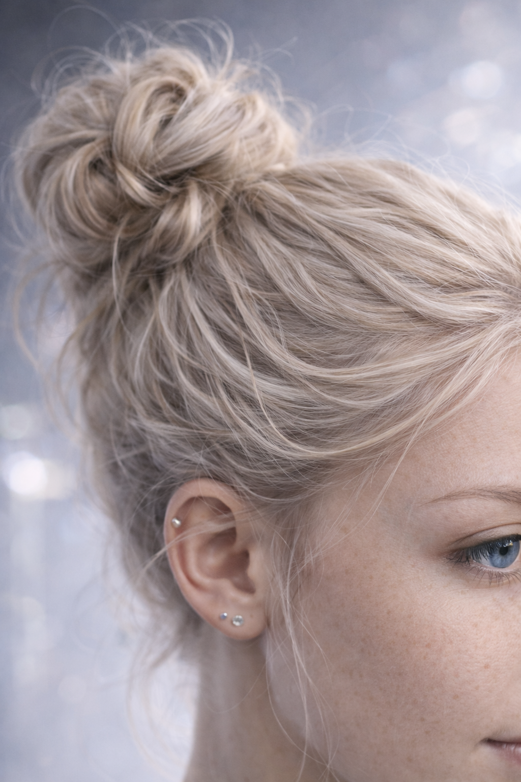 Close-up of a woman with platinum blonde hair styled in a messy bun, showing her ear with multiple piercings and her blue eye. AI influencer, AI persona, AI design, custom AI.