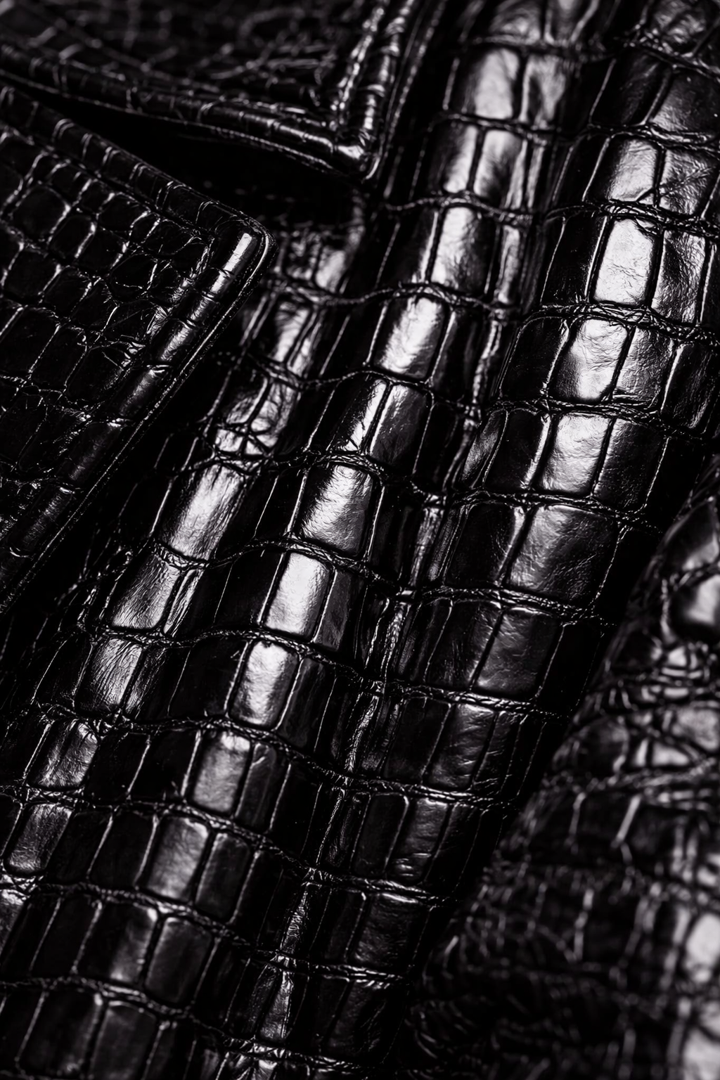 Close-up of glossy black crocodile leather material with textured pattern. Custom AI influencer, persona, content creator, brand ambassador.