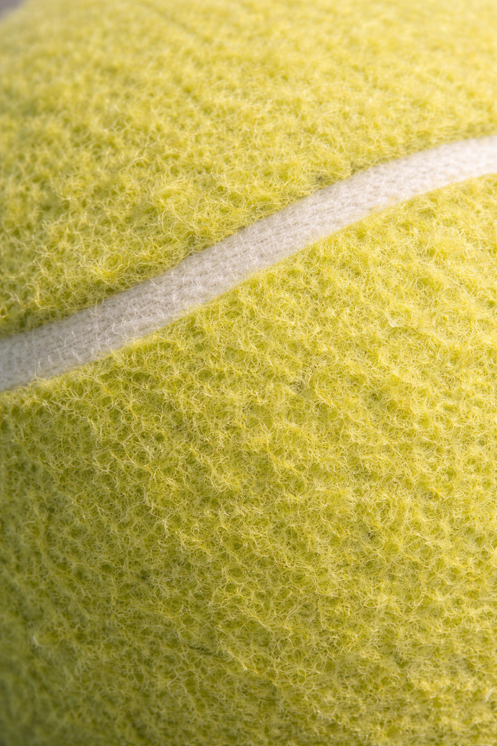 Close-up of fuzzy, yellow-green tennis ball surface showing fabric texture and white seam. Custom AI influencer, Custom AI persona, Custom AI identity. 