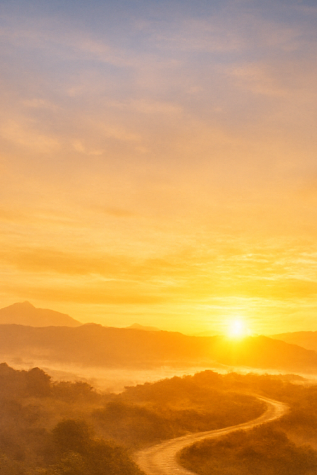 A scenic sunset over mountains with a winding road in the foreground and a sky filled with soft clouds.
