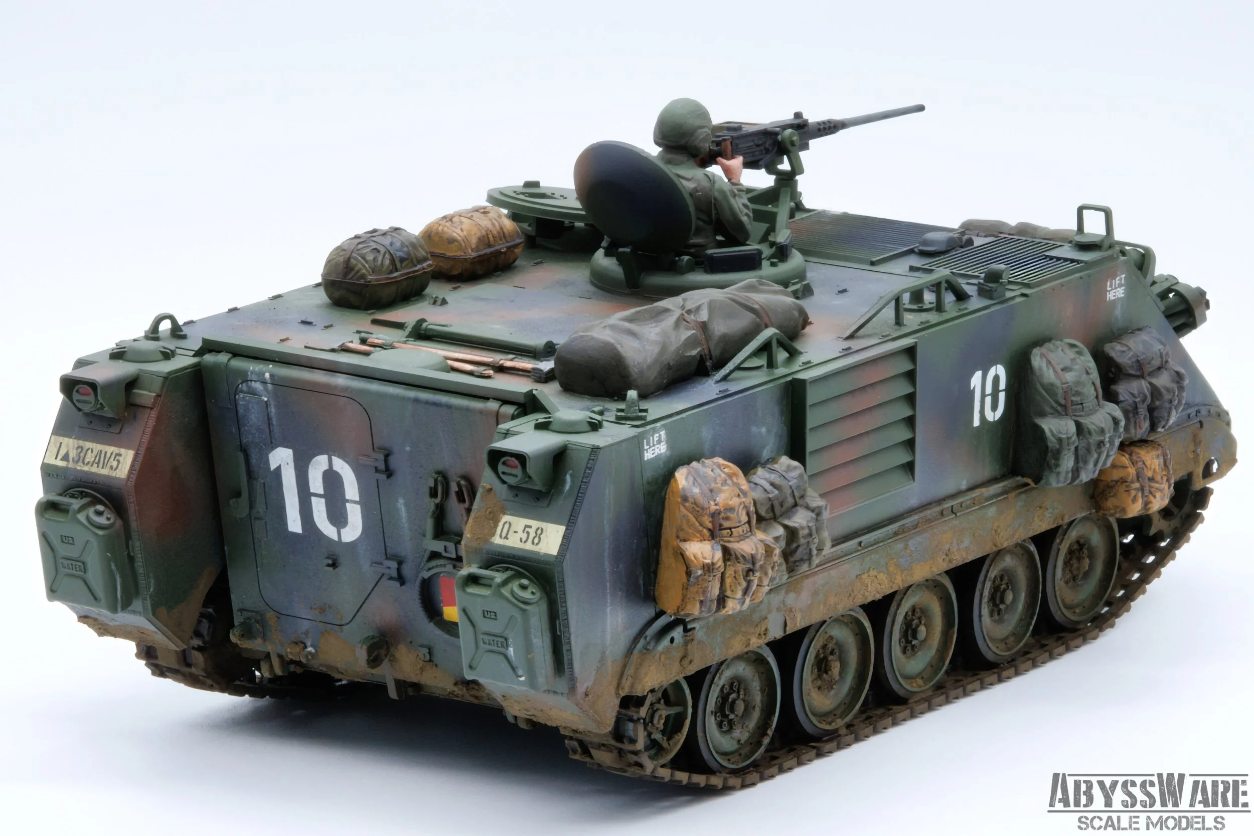 Scale model of a military armored vehicle with a mounted soldier figure aiming a rifle, detailed with camouflage paint, luggage, and equipment, on a white background.
