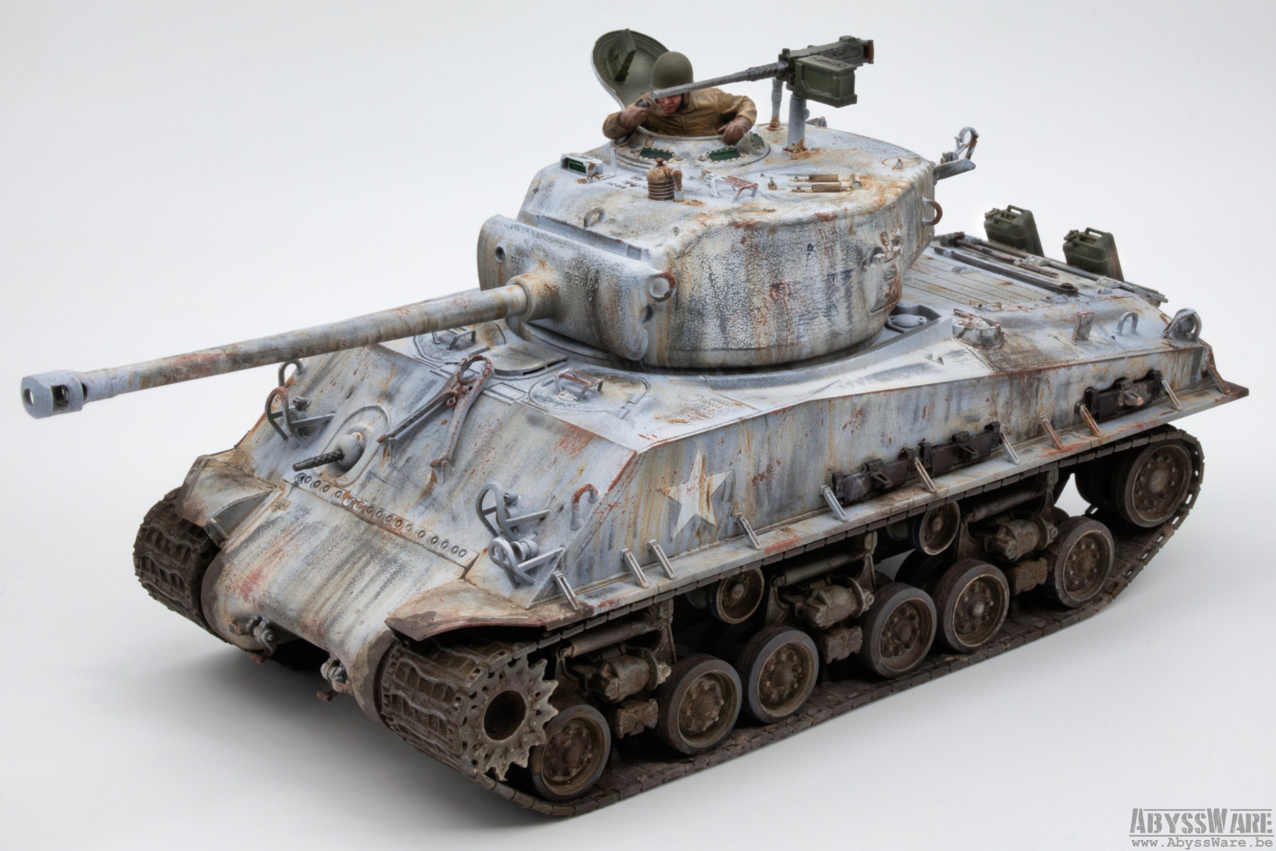 A detailed scale model of a World War II-era tank with a weathered, rusted appearance, featuring a soldier figure peeking out of the open hatch.