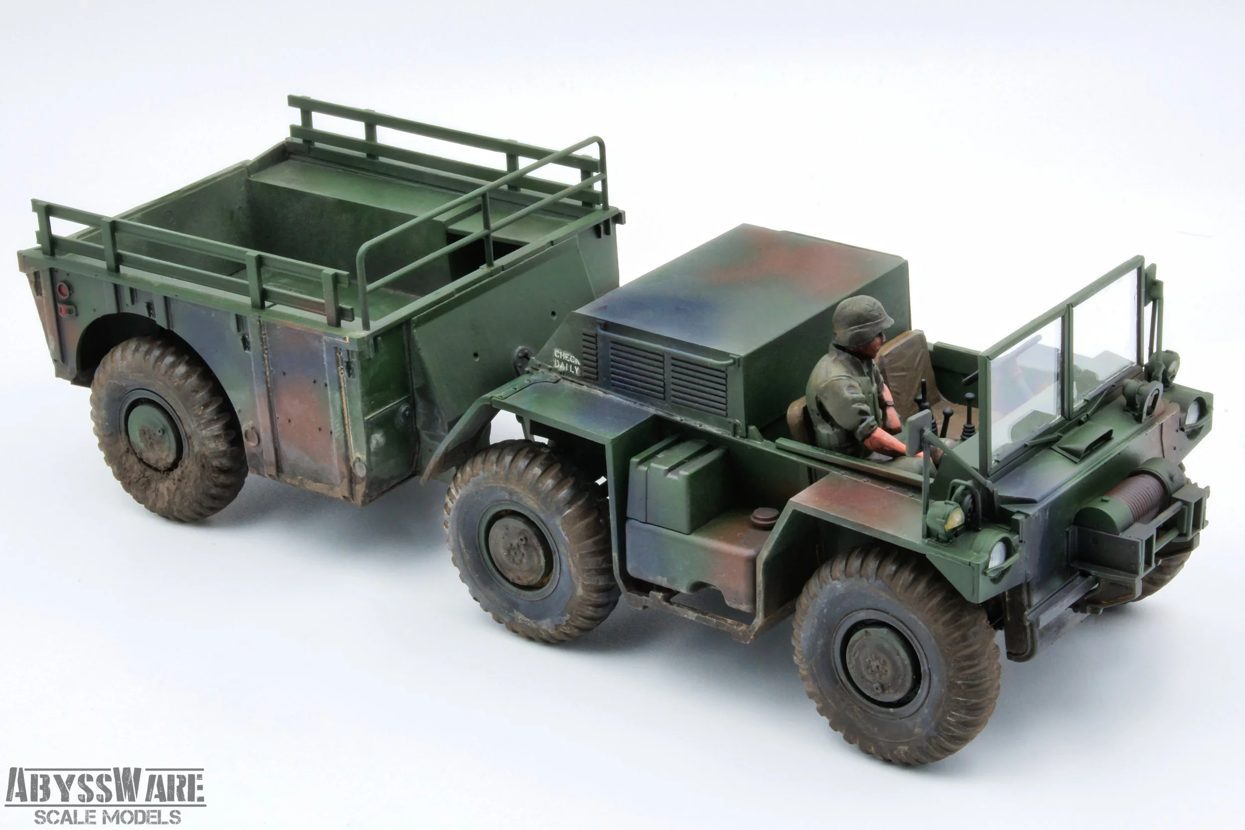 Scale model of a military green four-wheel drive truck with a driver figure inside, set against a plain white background. The model includes detailed military features and weathering effects.