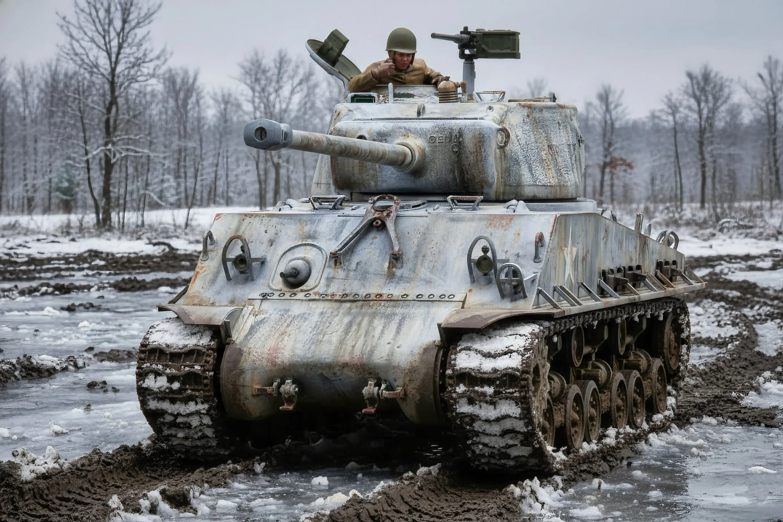 A soldier inside a weathered, rusty tank moving through a muddy, snowy landscape in winter with bare trees in the background.