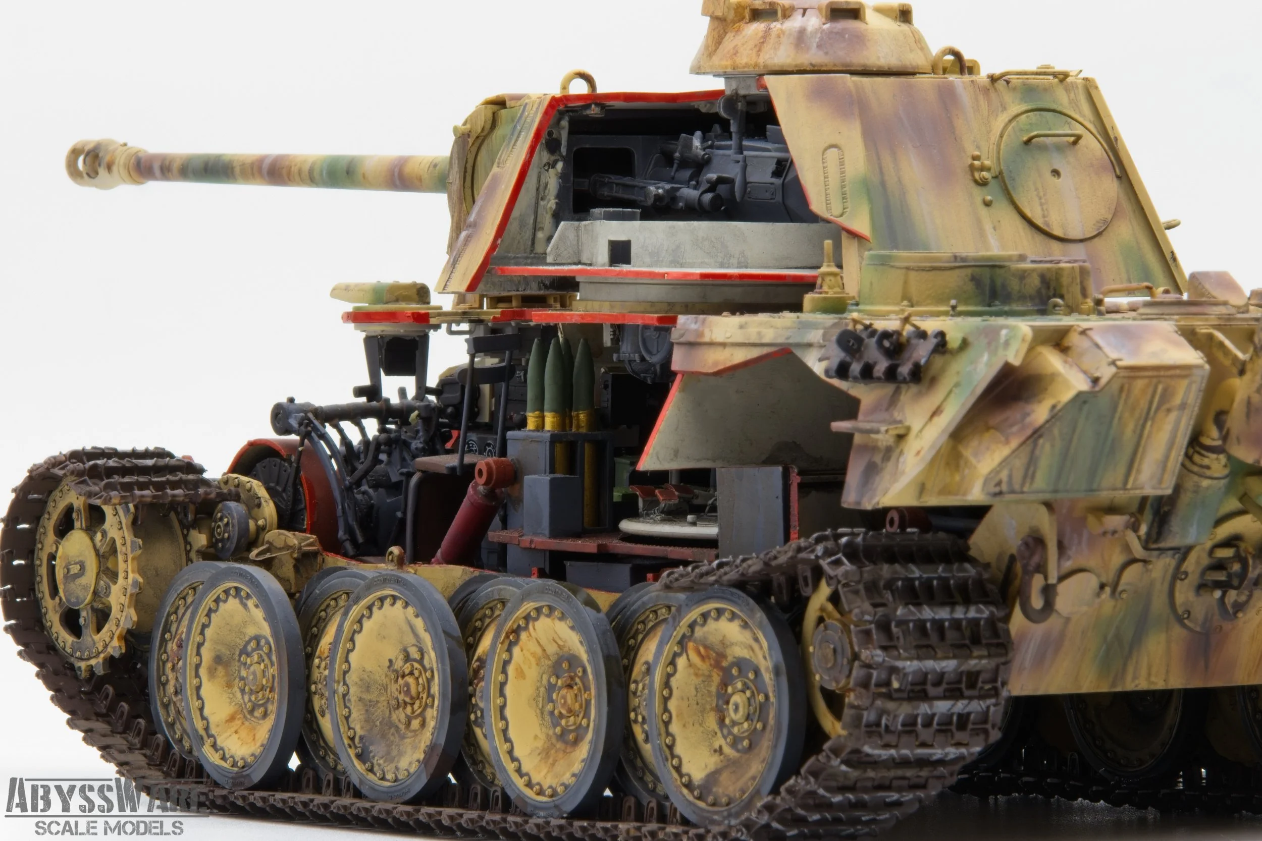 Close-up of a detailed scale model of a military tank with camouflage paint, visible tracks, and interior components including a machine gun and ammunition.