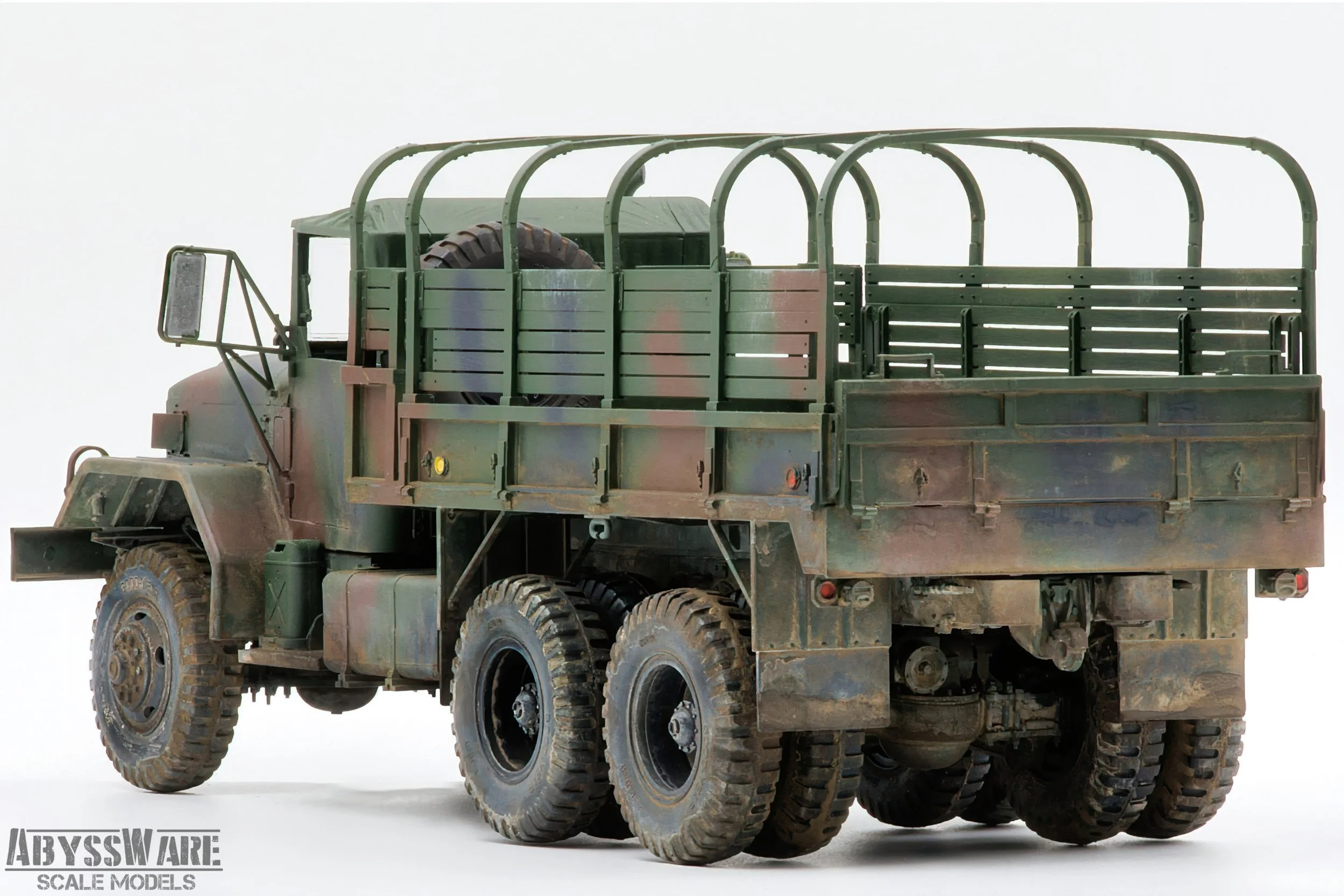Scale model of a military off-road cargo truck with a camouflage paint job, large tires, and a cargo area with a spare tire inside. The logo 'Abysware Scale Models' is visible in the bottom left corner.
