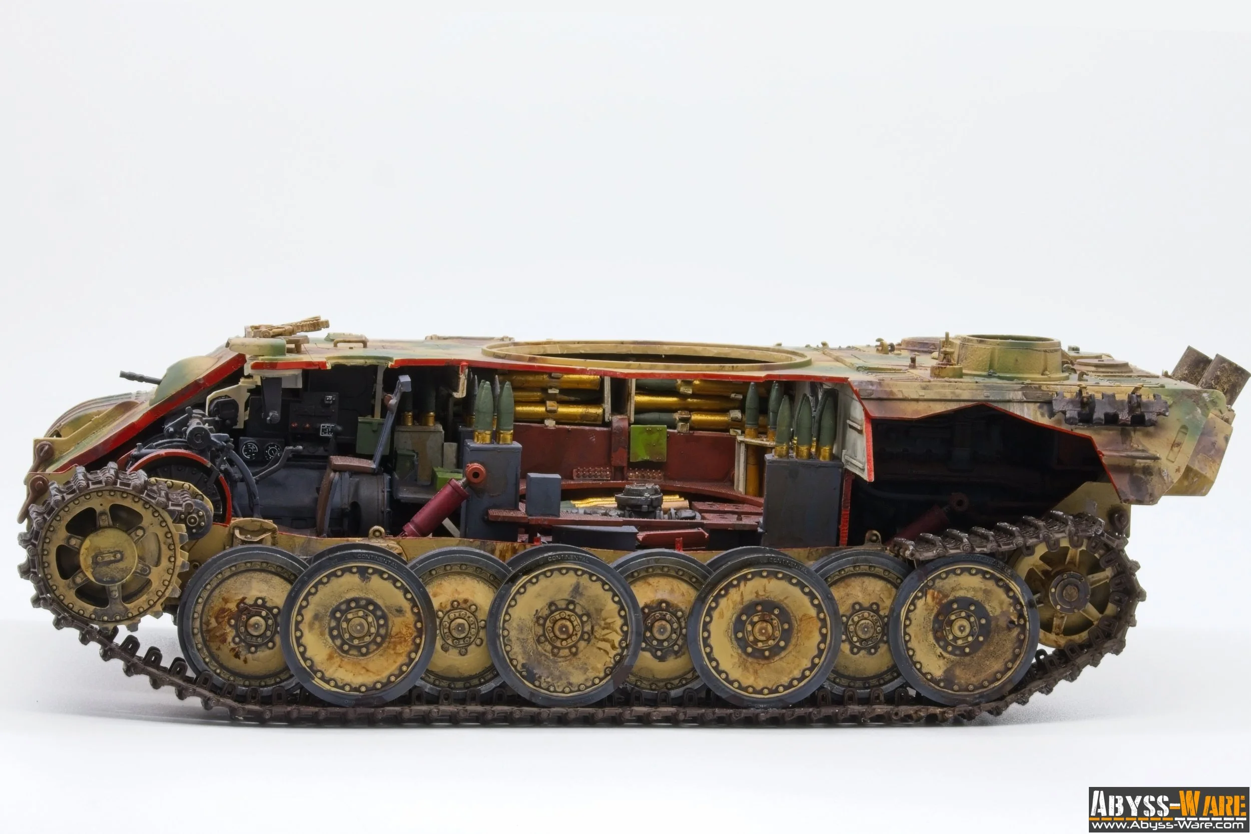 Side view of a detailed model tank with visible gears and components, painted in camouflage colors.