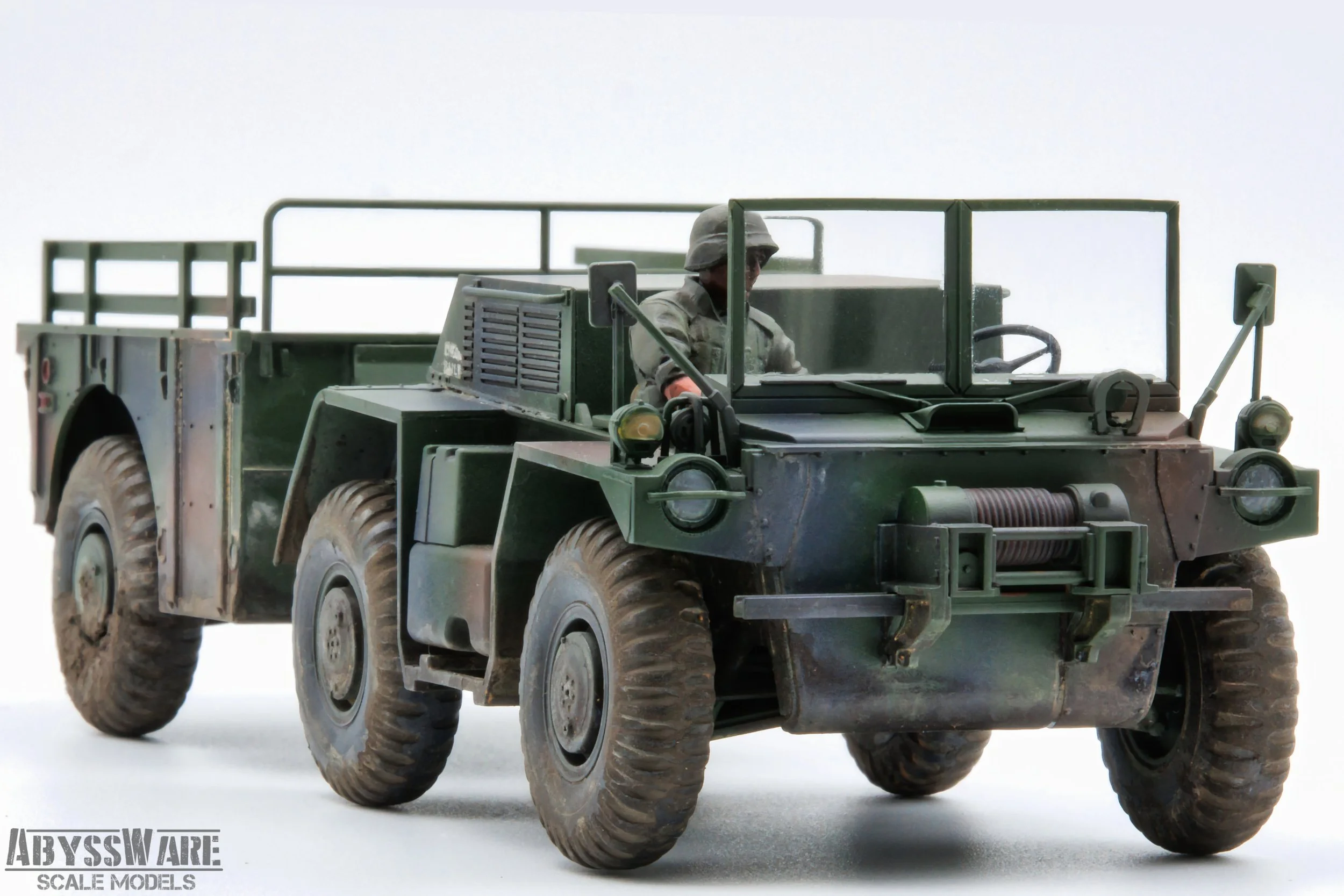 Scale model of a military green armored truck with a soldier figure inside, set against a white background.