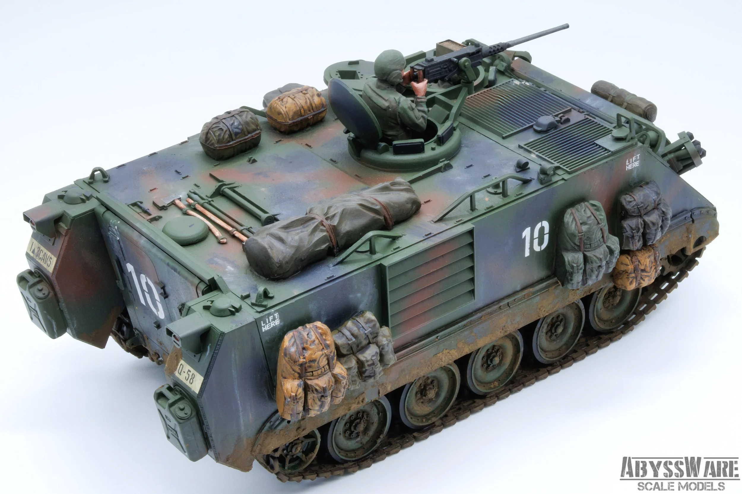 A detailed scale model of a military tank with a soldier figure operating a mounted machine gun on top, set against a plain white background.