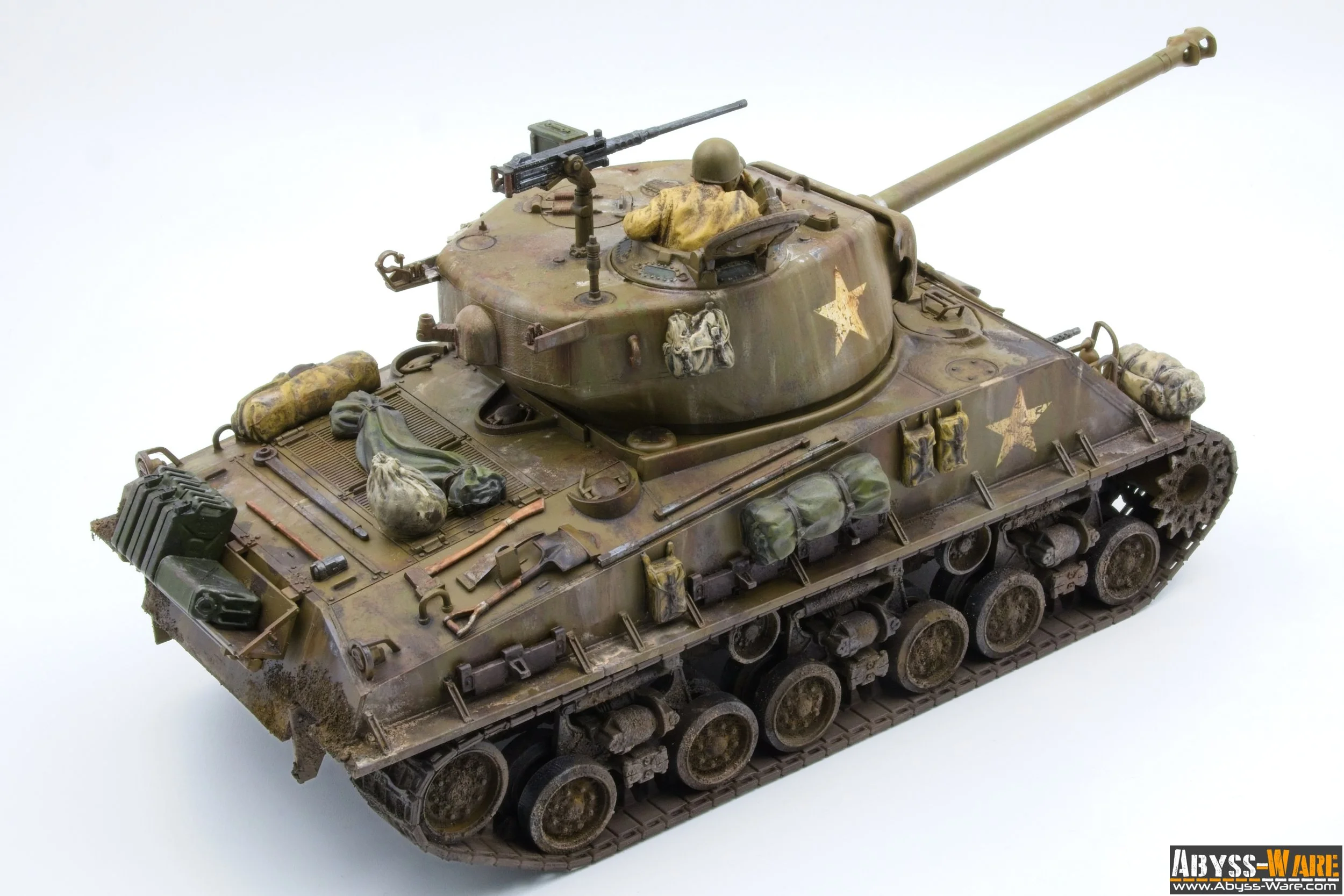 Detailed scale model of a military tank with camouflage paint, equipped with supplies and gear, featuring a turret with a soldier figure and a mounted gun, set against a plain white background.