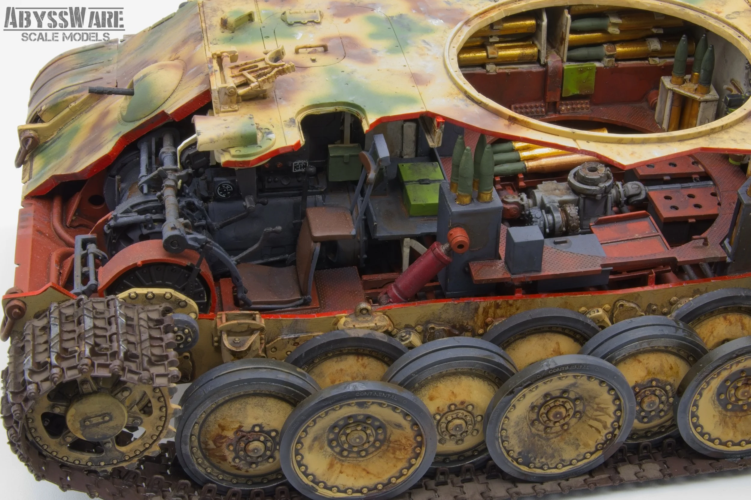 Close-up of a detailed scale model of a military tank, showing the interior and mechanical components, with a camouflage painted exterior and realistic tracks.