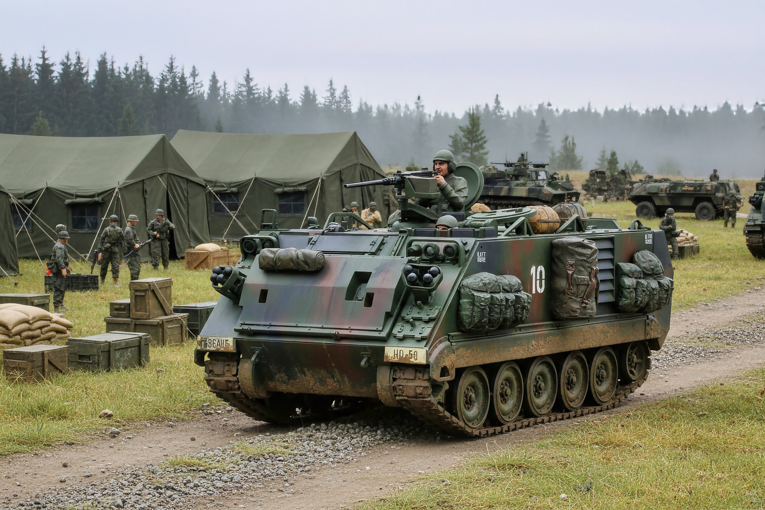 Military scene with a tracked armored vehicle in the foreground, soldiers in camouflage standing near tents in the background, and more military vehicles amid a forested area under a cloudy sky.
