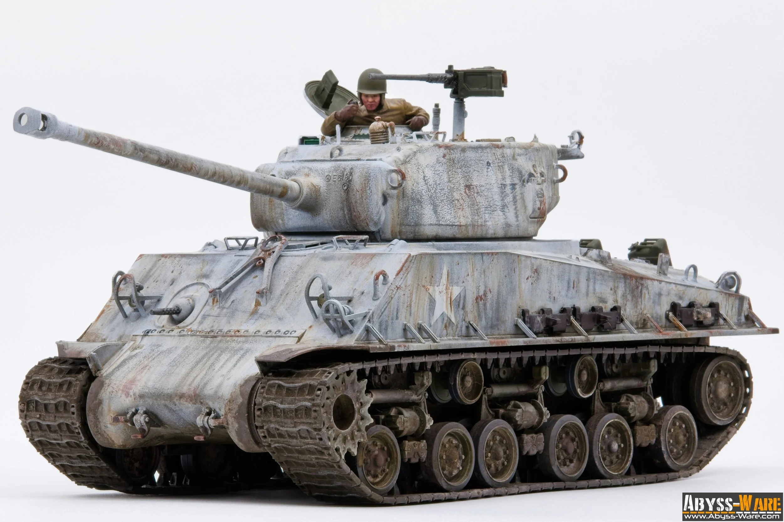 Model of a worn military tank with a soldier figure inside the turret, set against a plain white background.