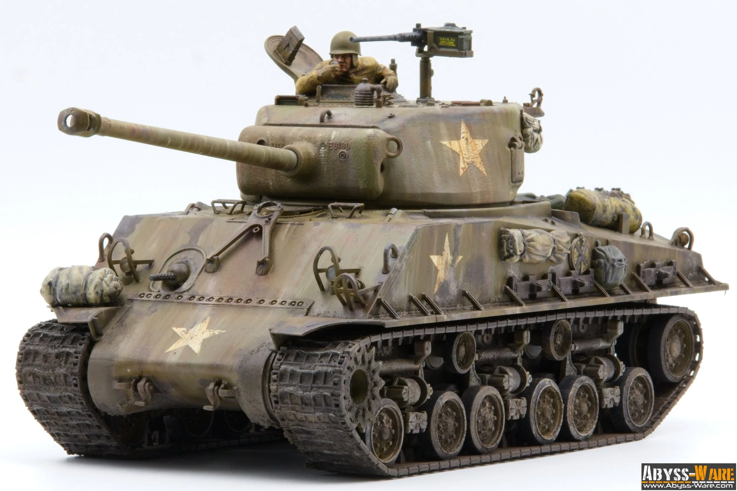 A detailed model of a military tank with a soldier figure in the turret, painted in camouflage with military markings, against a plain white background.