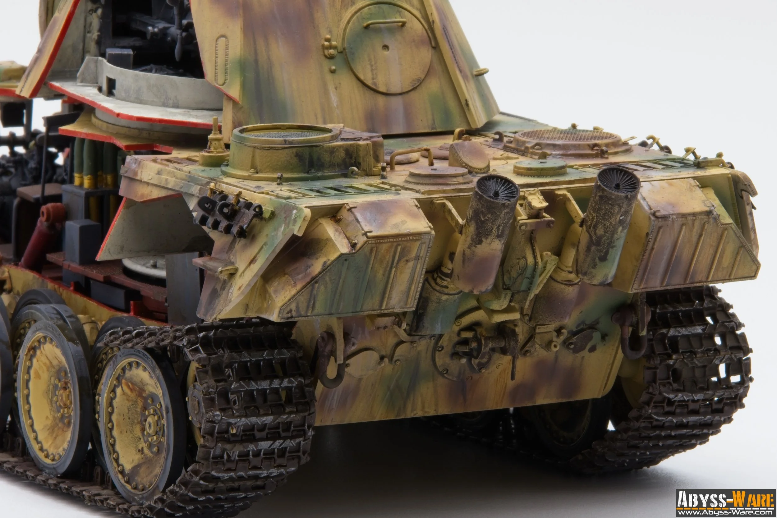 Close-up of a military tank displaying its front and side armor, tracks, exhaust pipes, and hatches, with a weathered camouflage paint job.