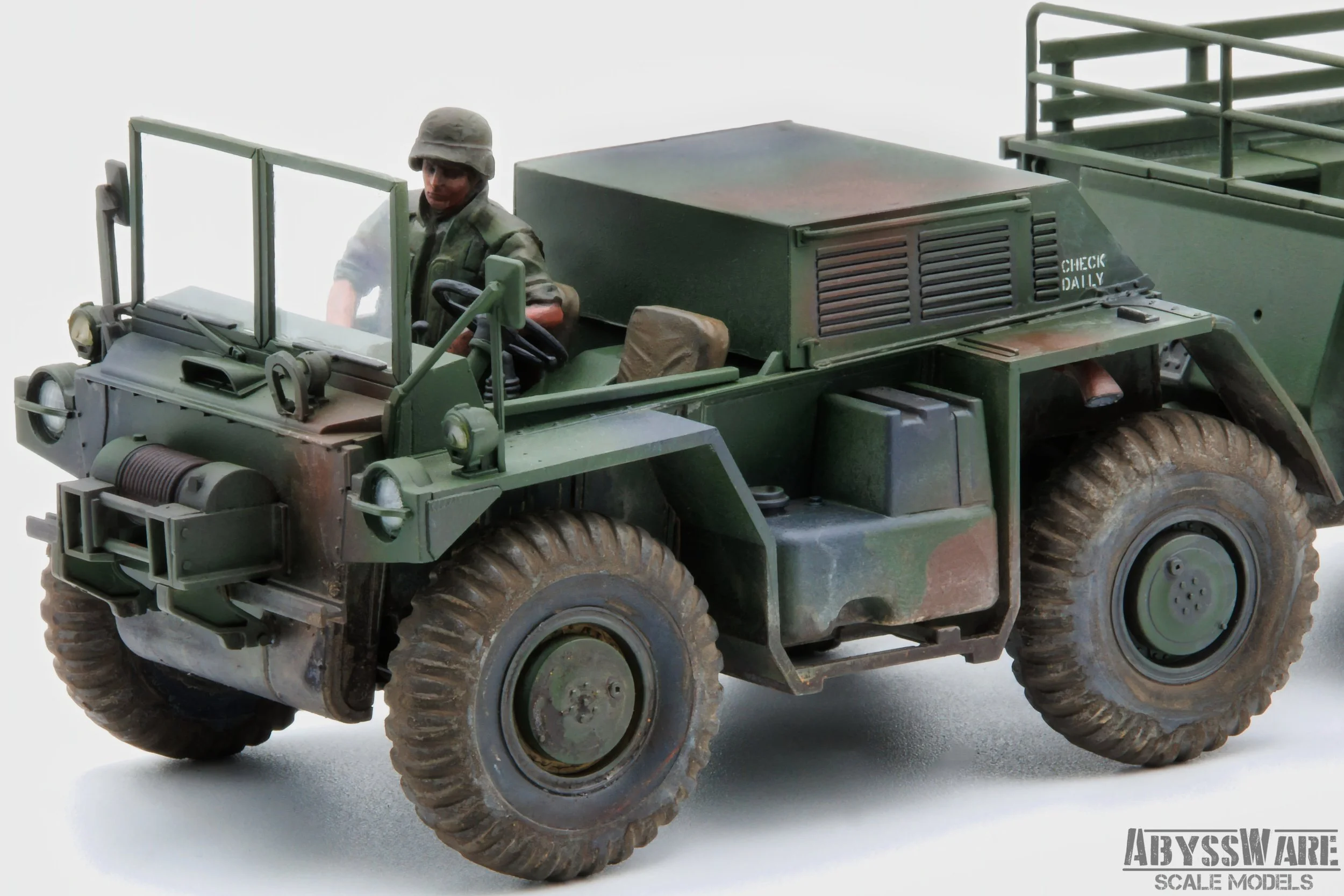 A detailed scale model of a military green off-road truck with a figurine of a soldier driving, featuring rugged tires, a windshield, and various equipment details.
