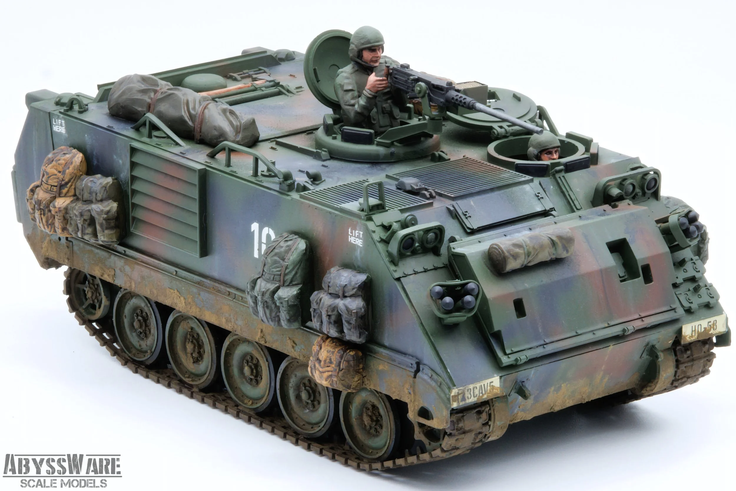 Scale model of a military armored vehicle with two soldiers, one with a mounted gun and the other peeking from a hatch, detailed with camouflage, equipment, and accessories, on a plain background.