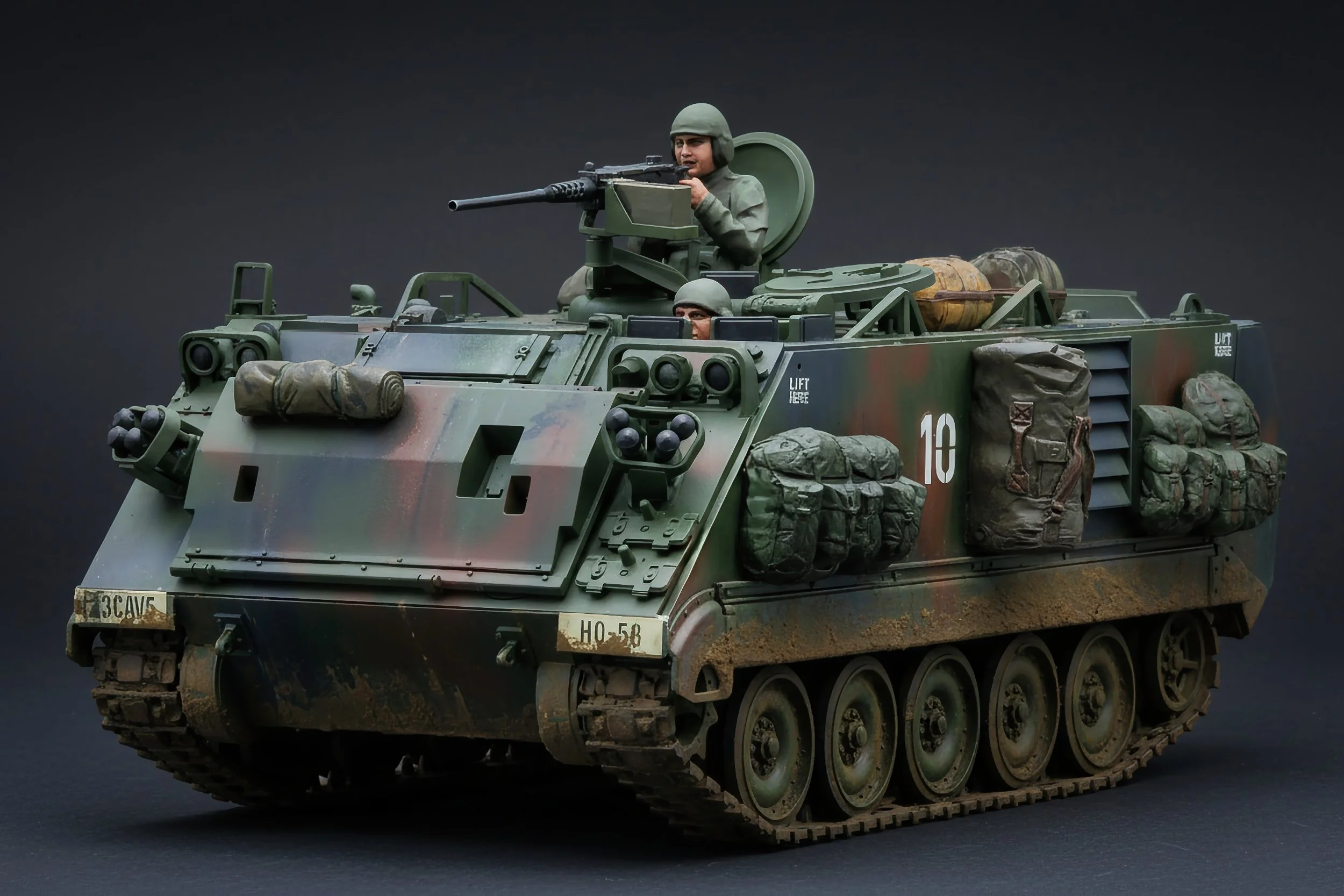 A detailed scale model of a military armored vehicle with camouflaged paint, equipped with soldiers, weapons, and cargo, set against a plain dark background.