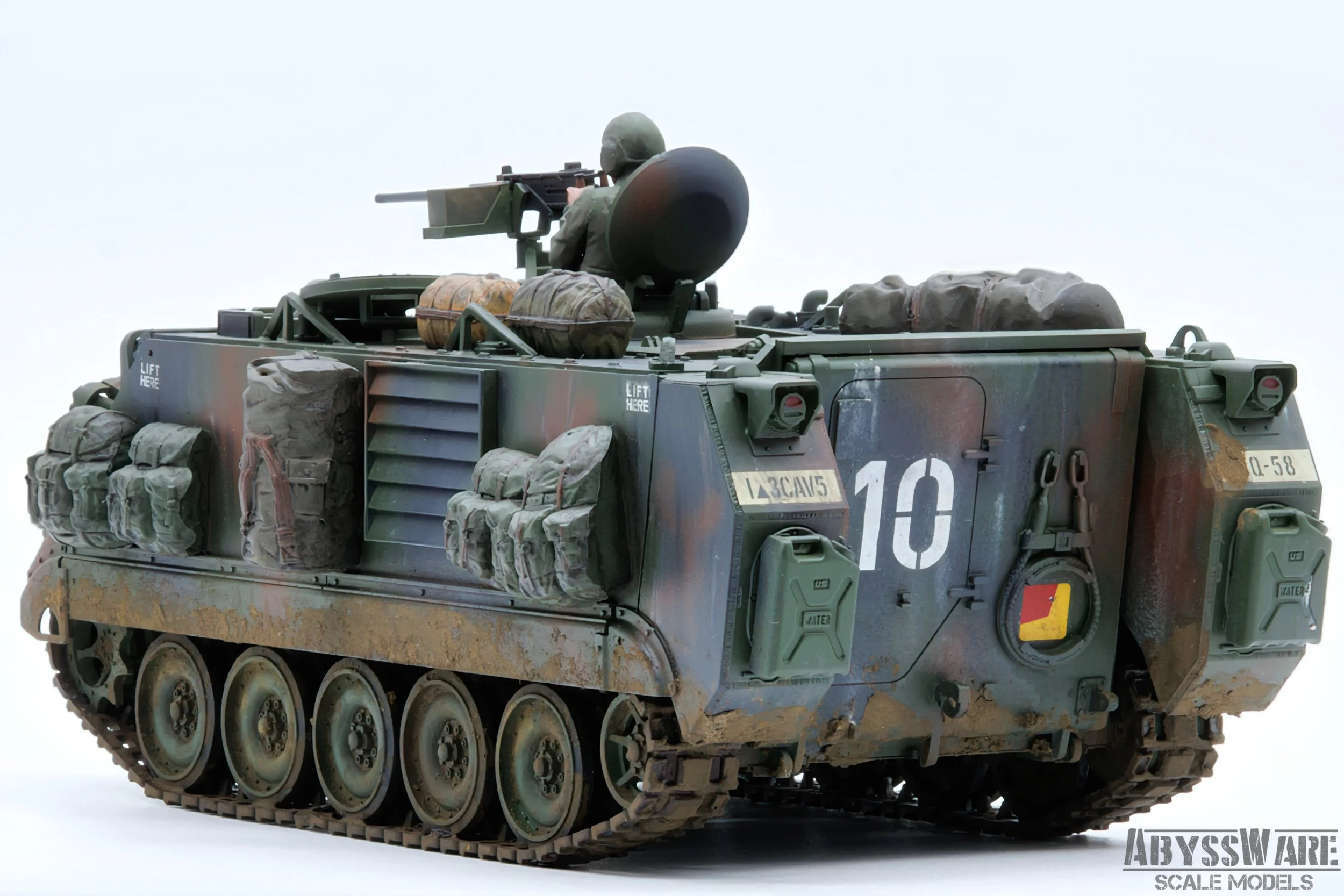 Scale model of a military armored tank with a soldier figure on top aiming a sniper rifle, detailed with various storage bags and markings, displayed against a plain white background.