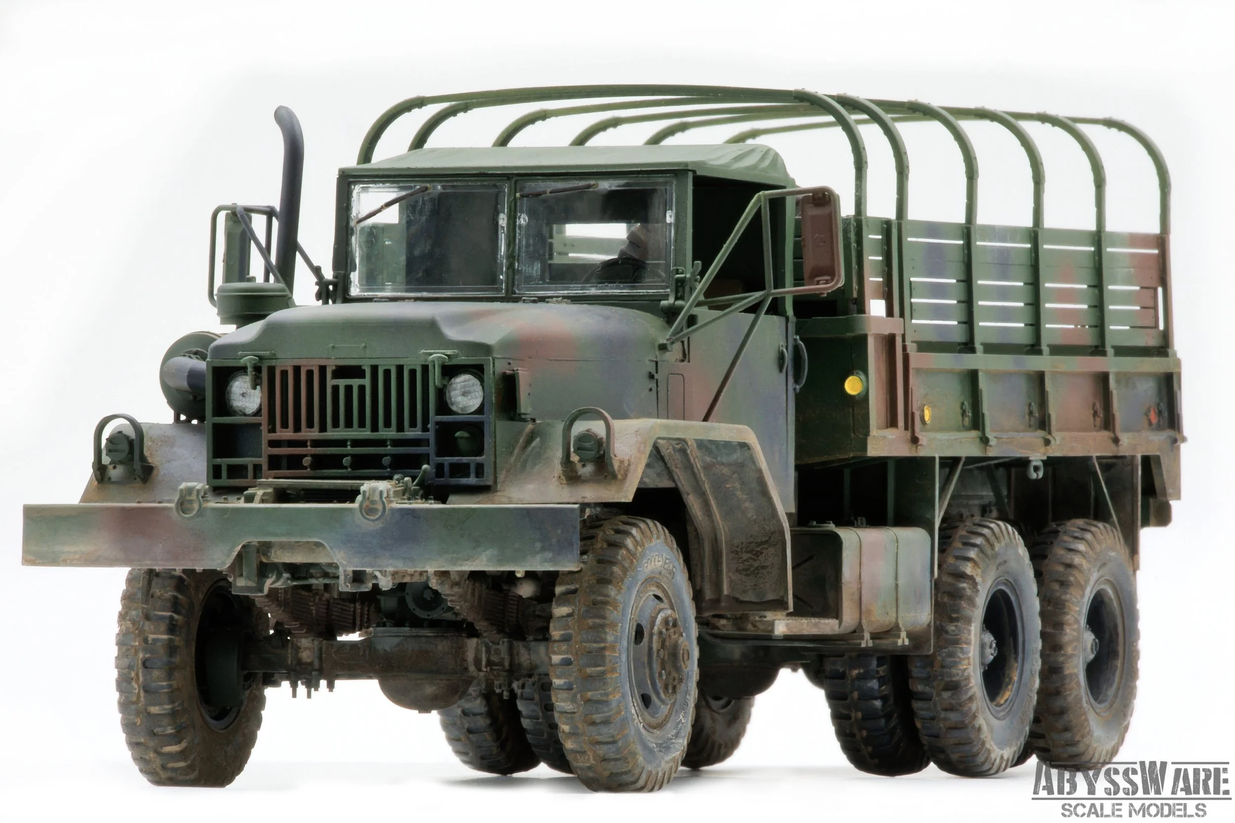 A scale model of a military cargo truck with a green camouflage paint job, large rugged tires, and an open flatbed area with side rails.