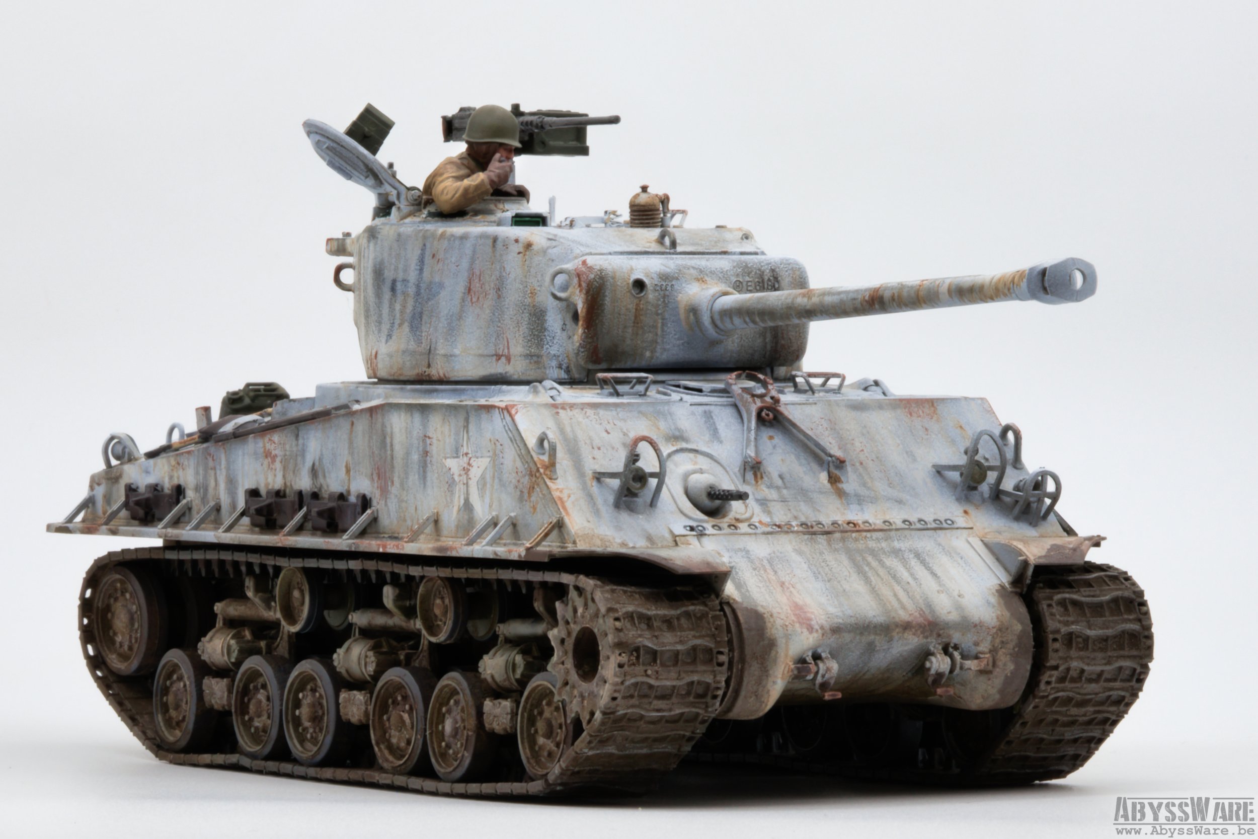 Model of a military tank with a soldier figure peeking out from the hatch, set against a plain background.