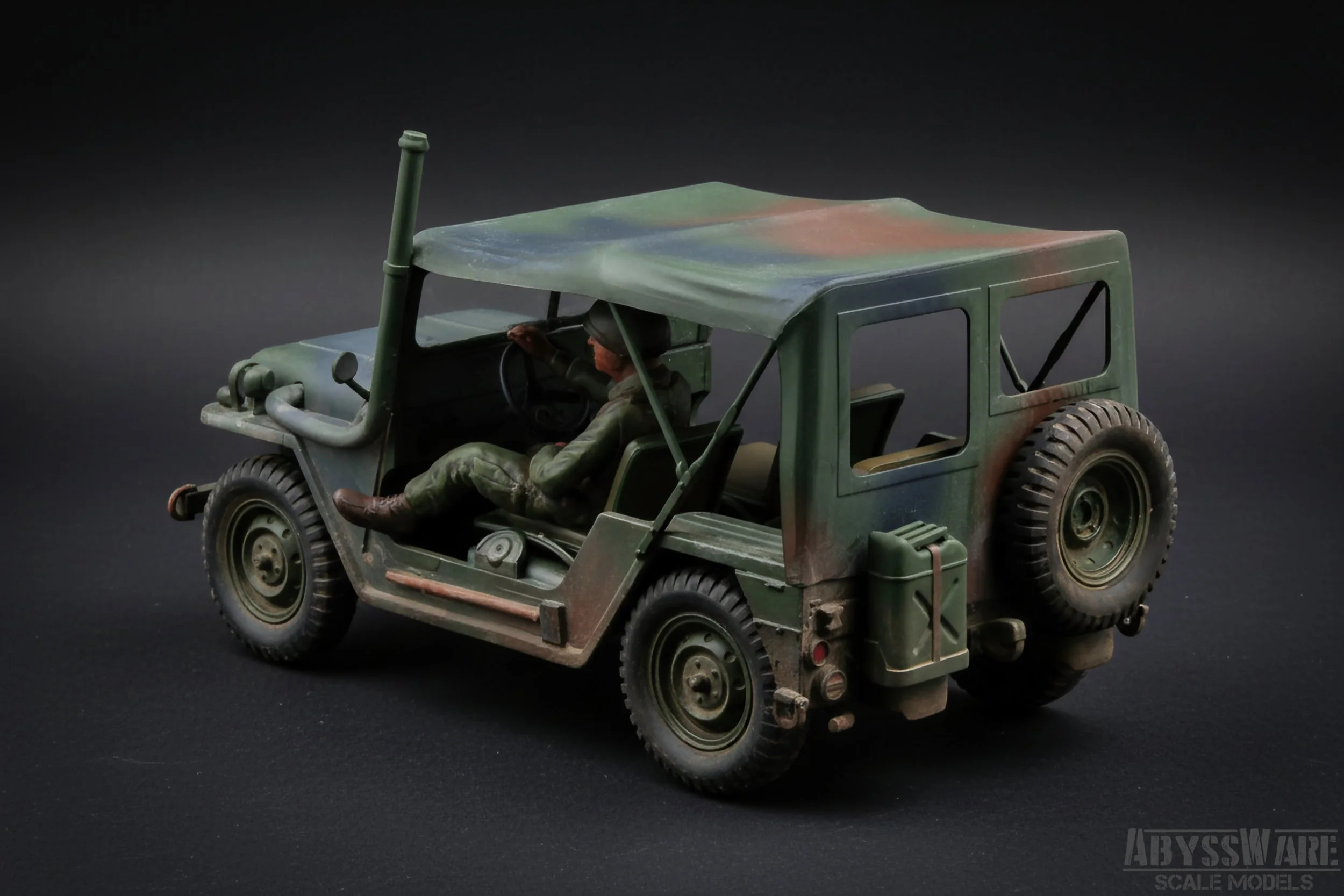 Model of a military jeep with a soldier figurine seated inside, painted in camouflage pattern, on a dark background.