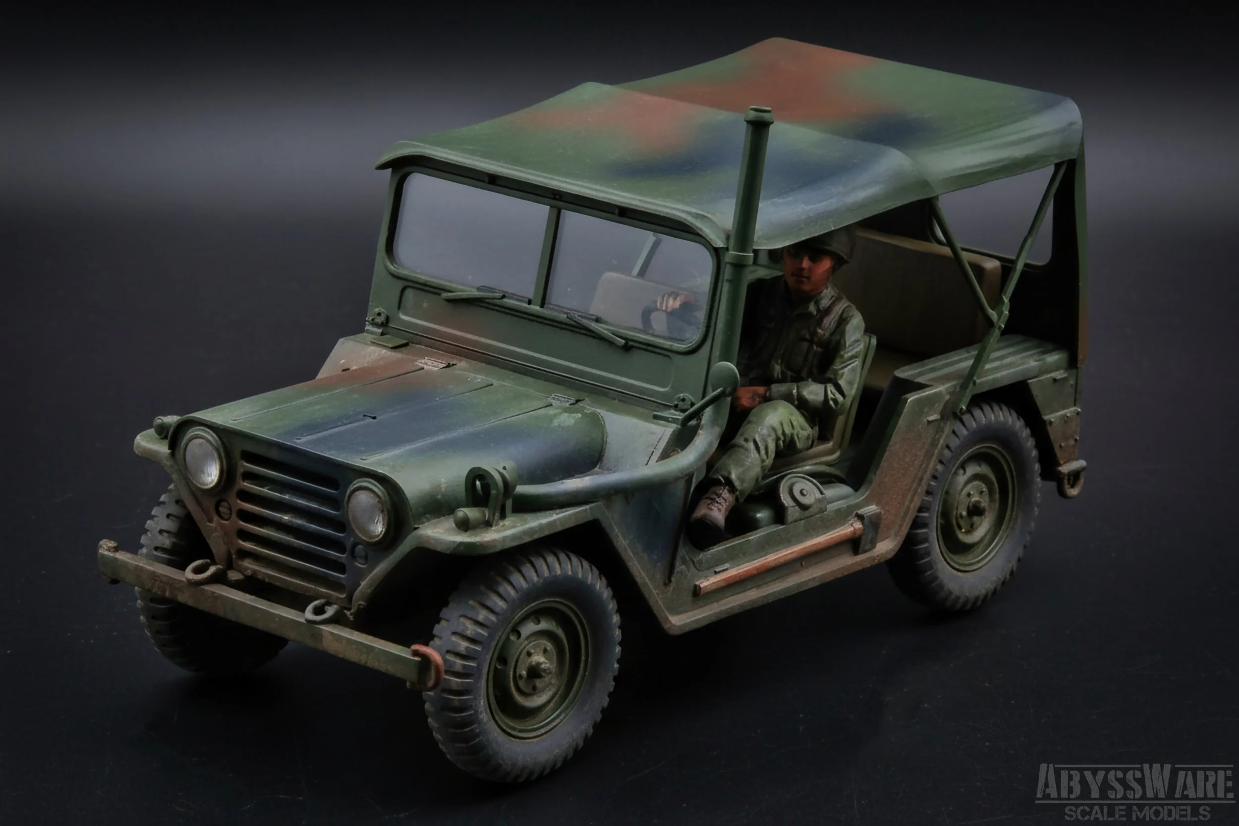 A detailed scale model of a military Jeep with a soldier figure inside, painted in weathered green camouflage on a black background.