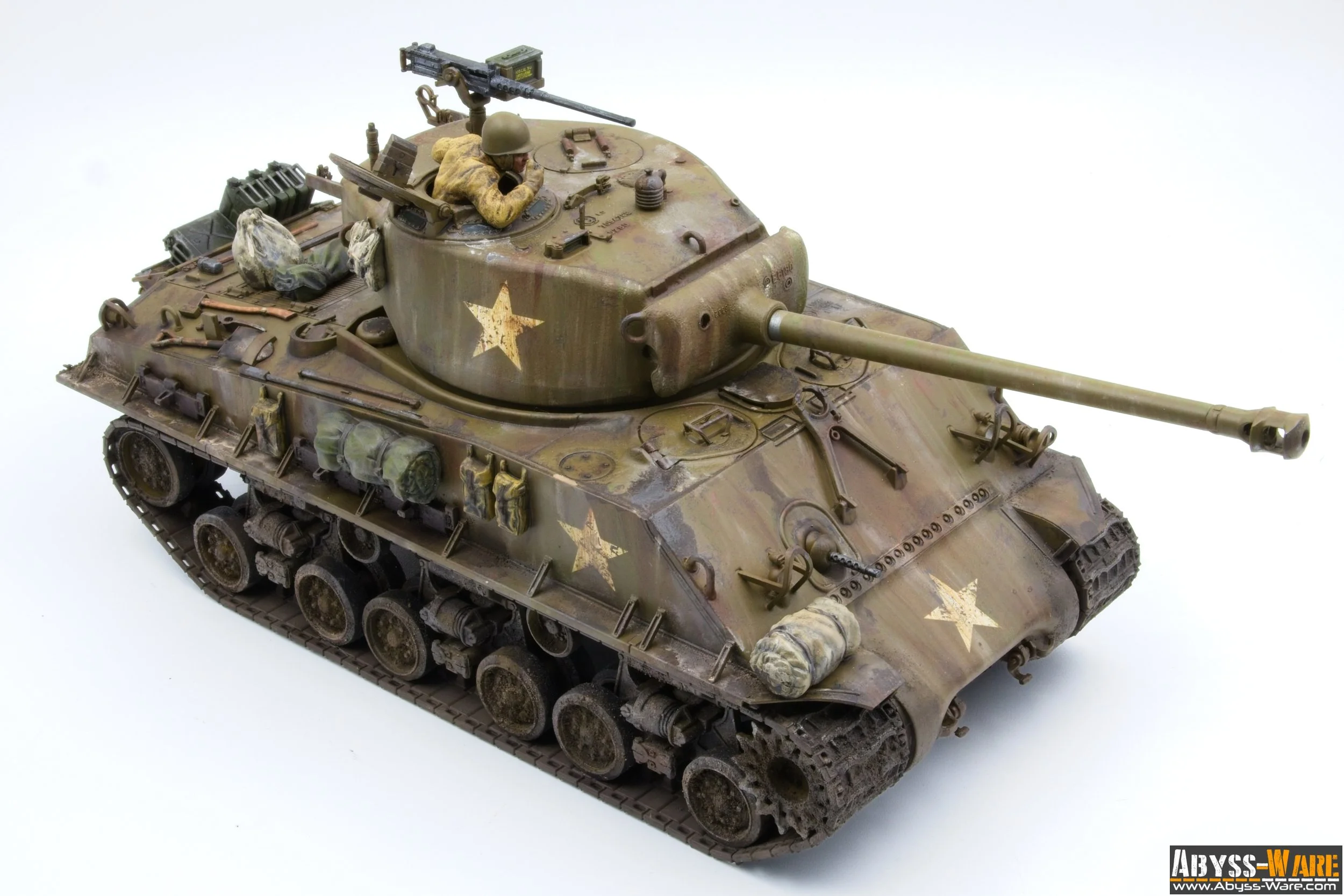 Model of a military tank with a soldier figure on top, painted in camouflage with yellow stars, placed on a white background.