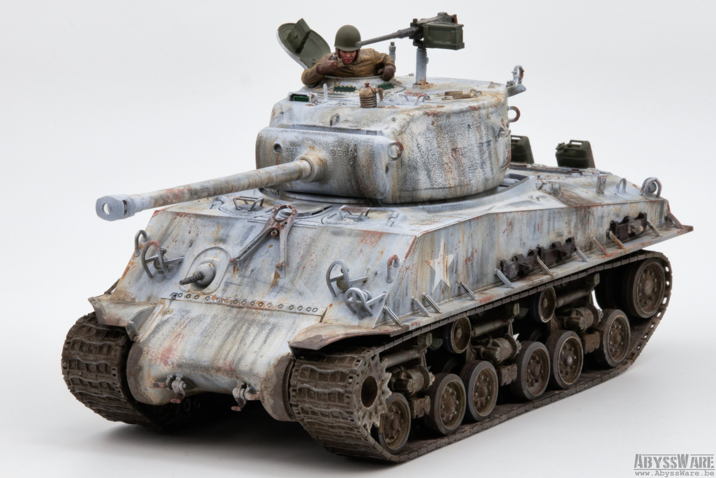 Model of a weathered, military tank with a soldier figure partially inside the turret, set against a plain white background.