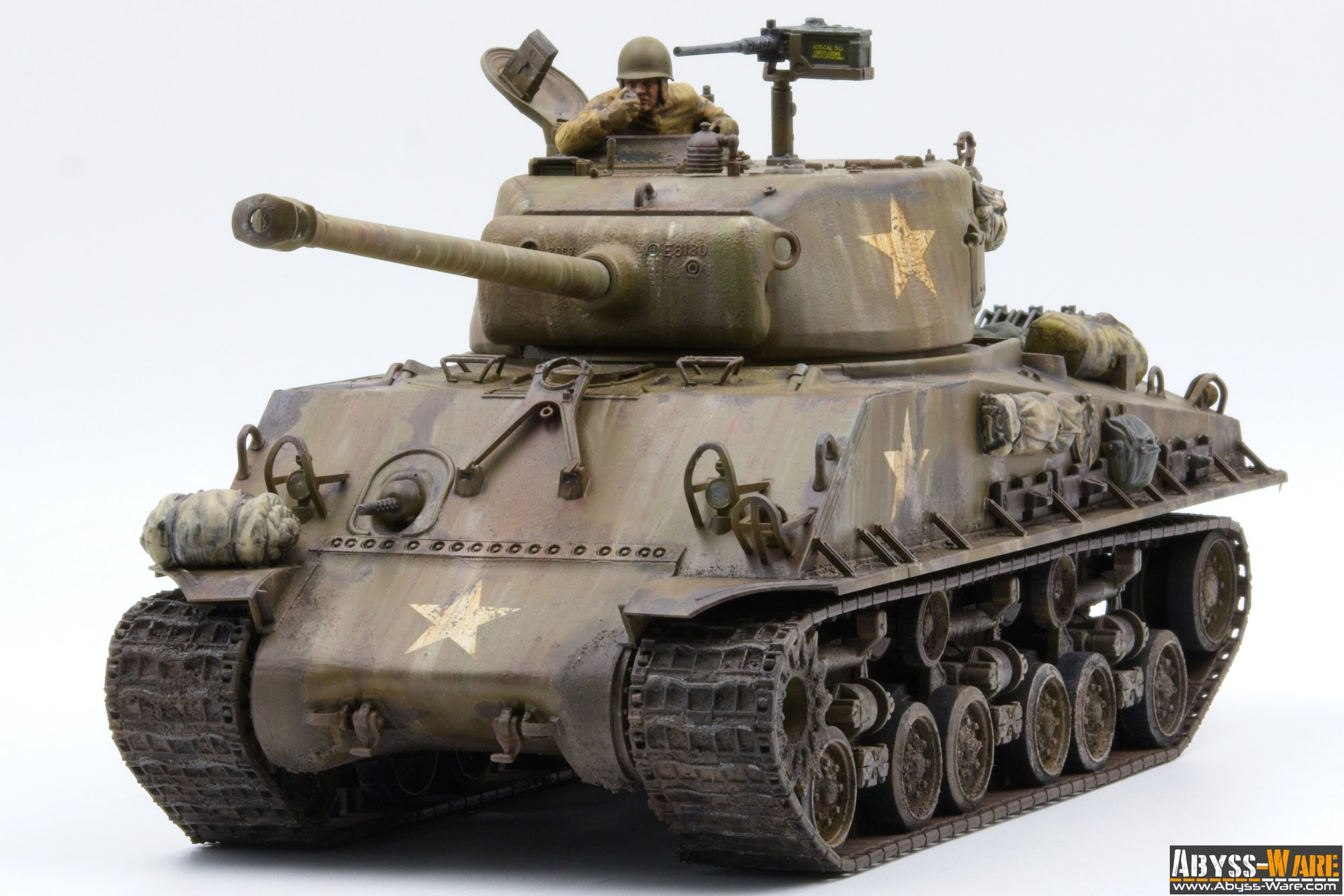 A detailed model of a military tank with a soldier figure in the hatch, painted in camouflage with star insignias, placed on a plain white background.