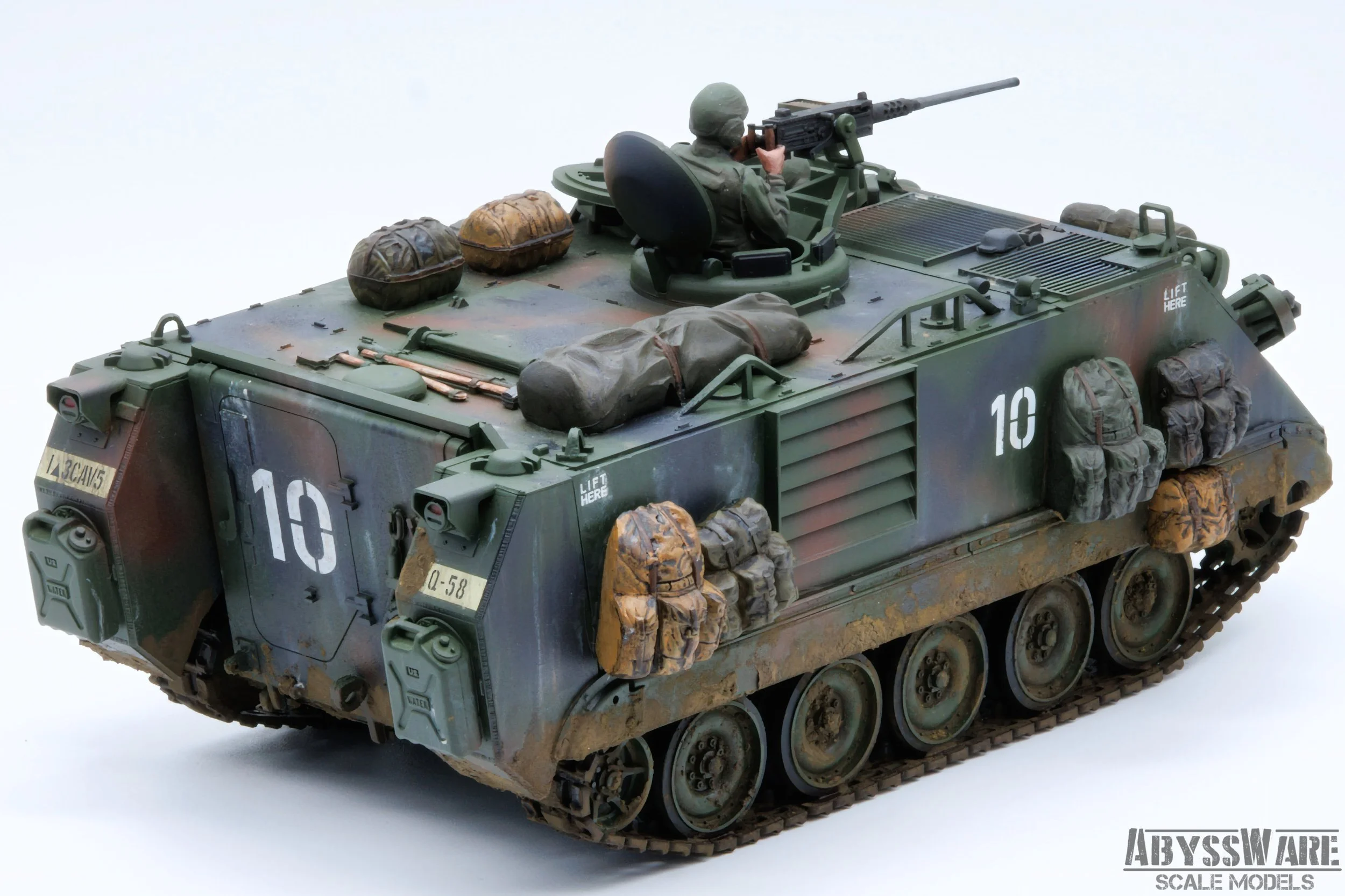 Scale model of a military armored vehicle with a soldier figure manning a mounted gun on top, decorated with gear and camouflage paint.