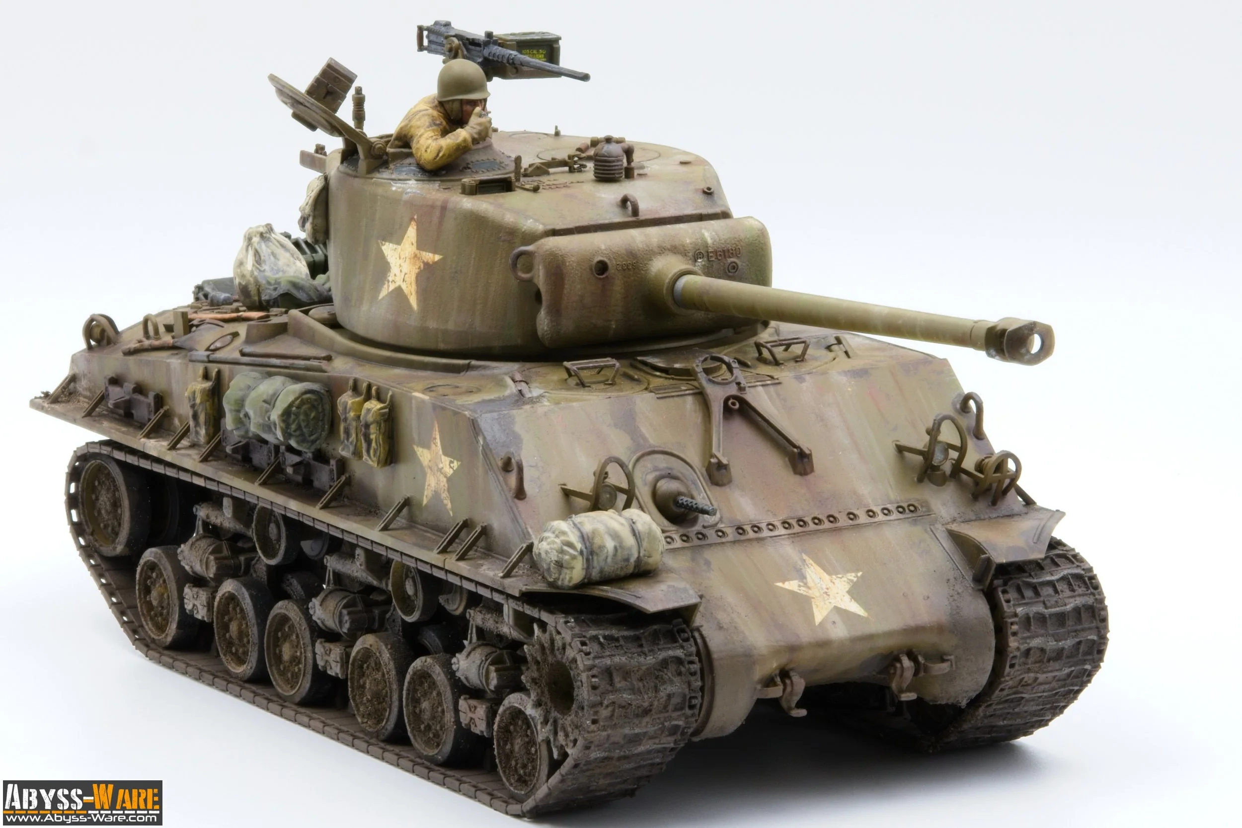 Model of a military tank with a soldier figure sticking out of the hatch, painted in desert camouflage with yellow stars on the side, mounted with a long barrel, and placed against a plain white background.