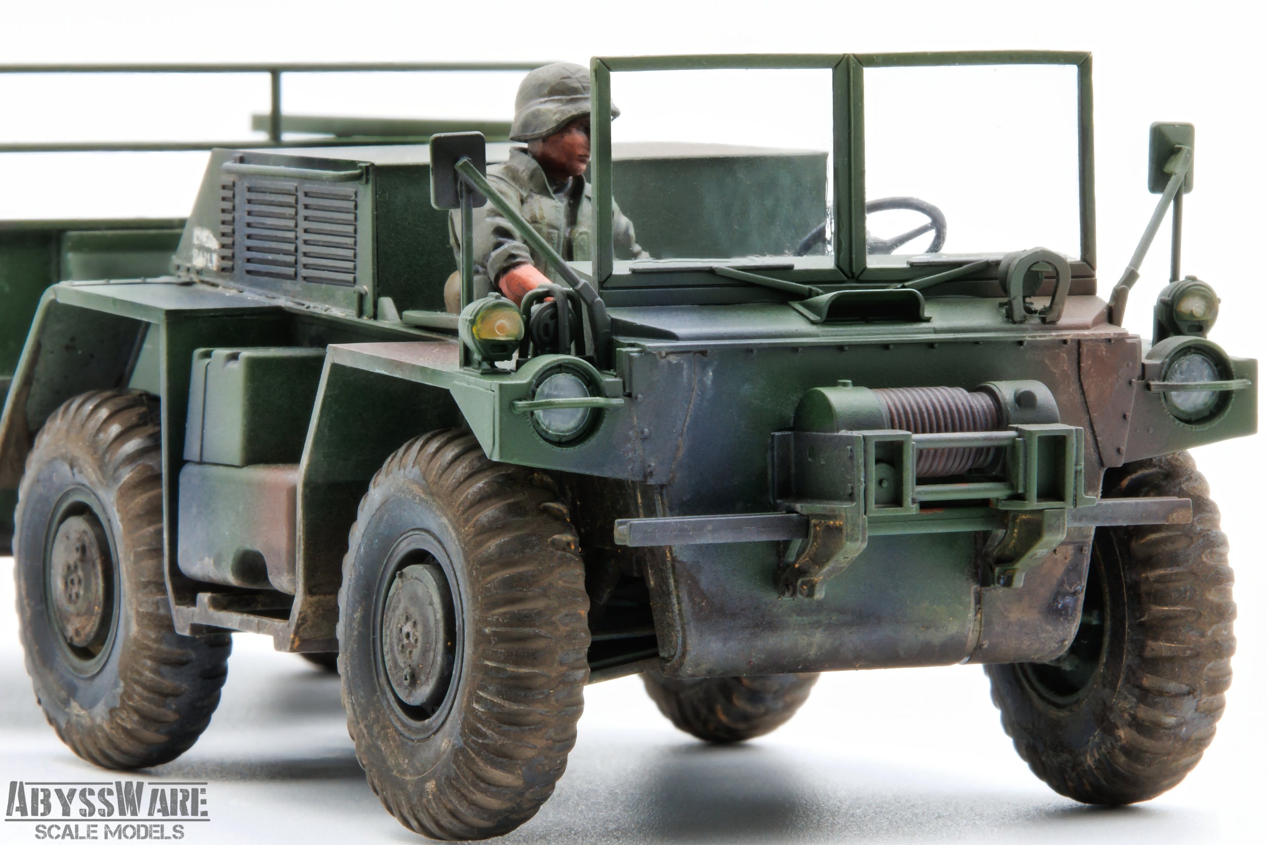 A scale model of a military jeep with a driver figurine wearing a helmet and military uniform, set against a plain background.