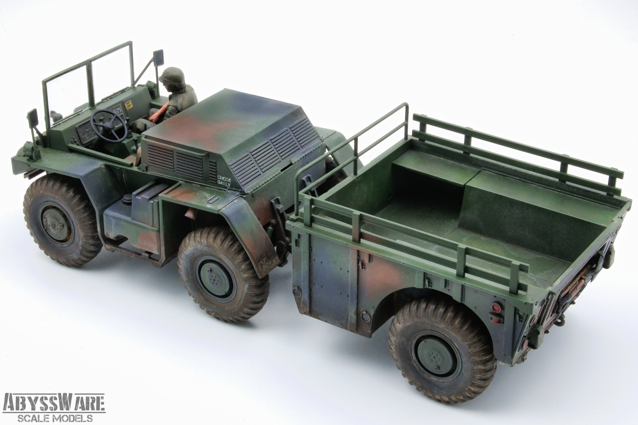 Scale model of a military green pickup truck with an open cargo bed, a driver figure, and large rugged tires on a white background.