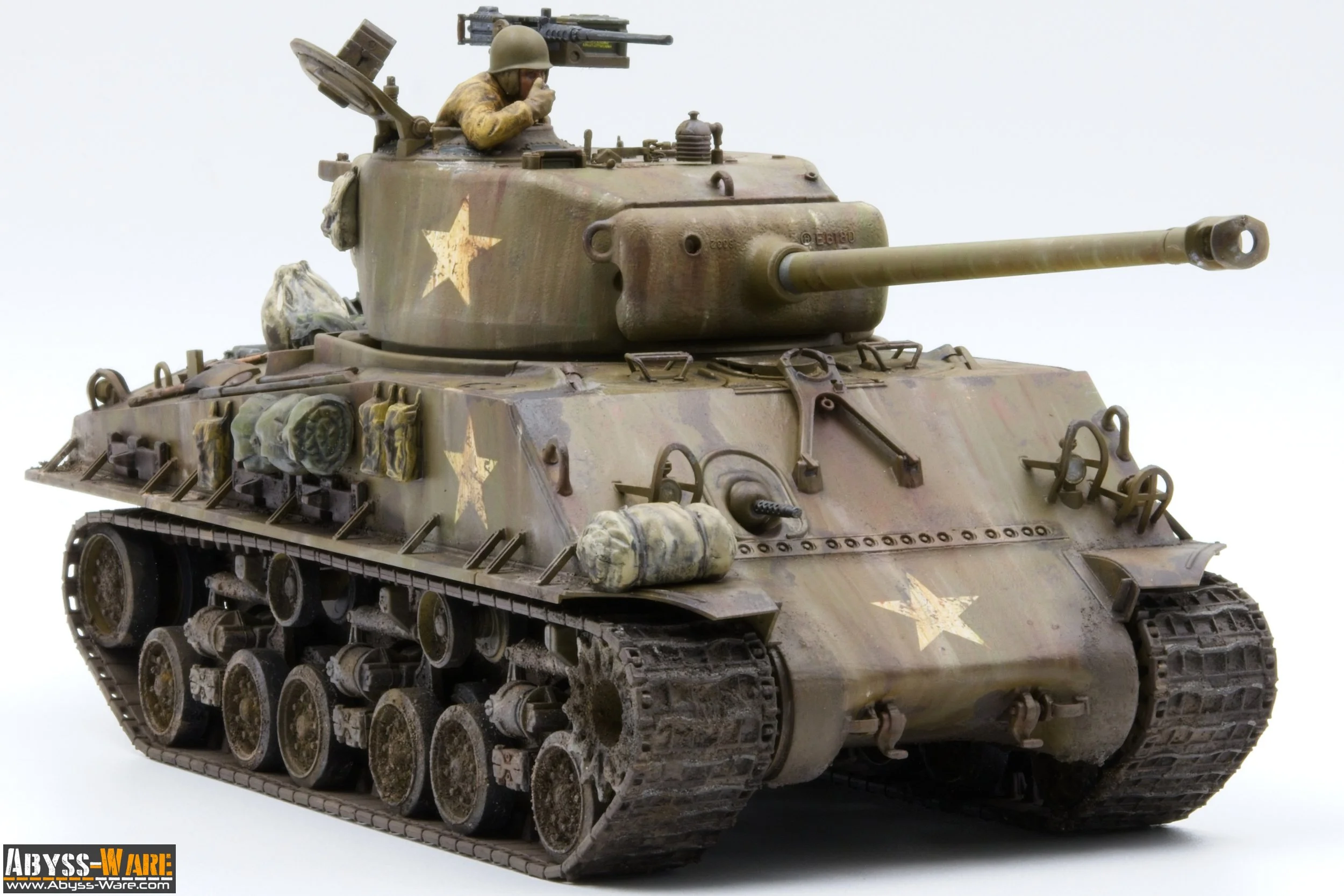 A detailed model of a military tank with a soldier figurine inside the turret, featuring various tools, supplies, and camouflage markings, against a plain white background.