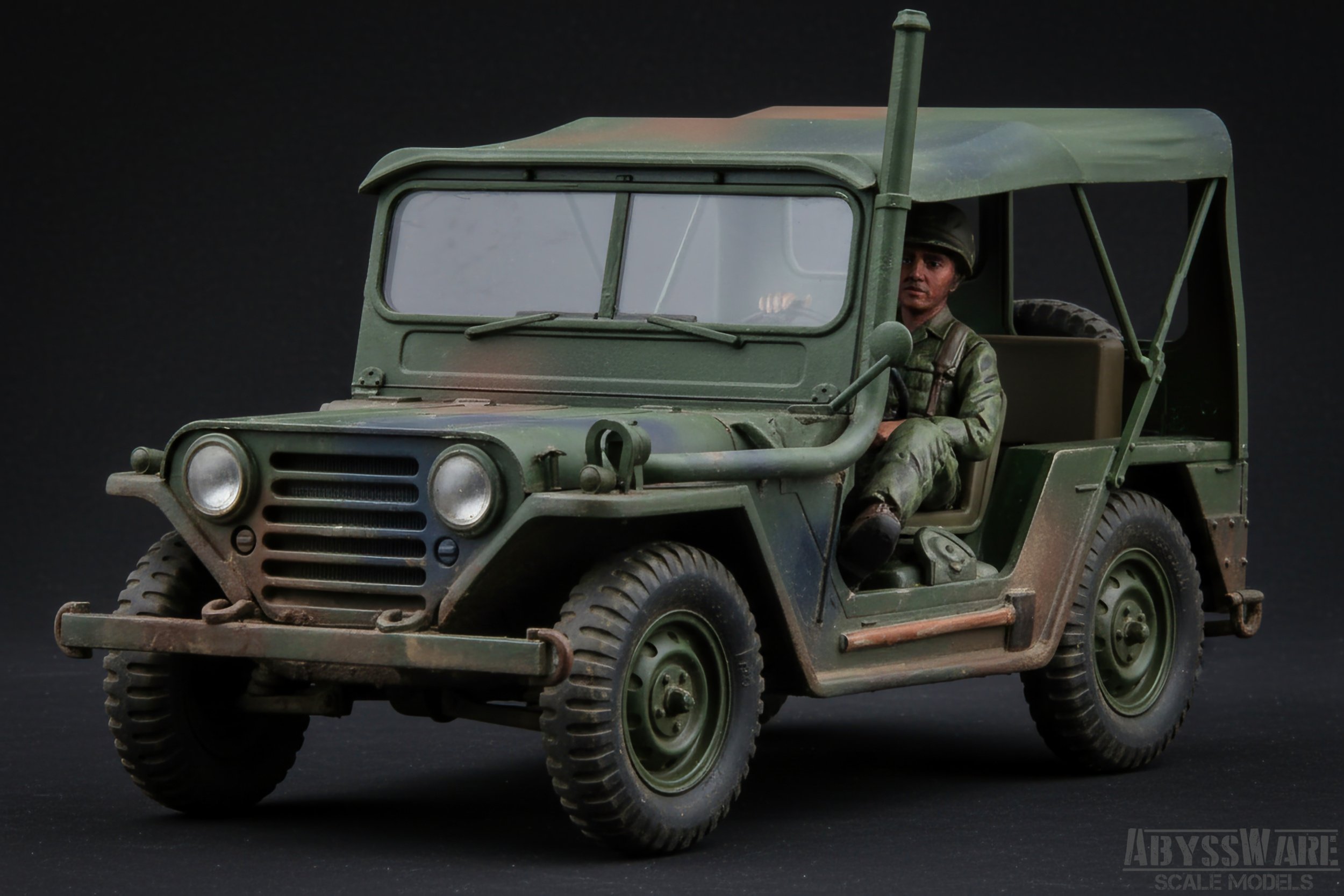 Model of a vintage military Jeep with a soldier figure seated inside, painted in green camouflage with a black background.