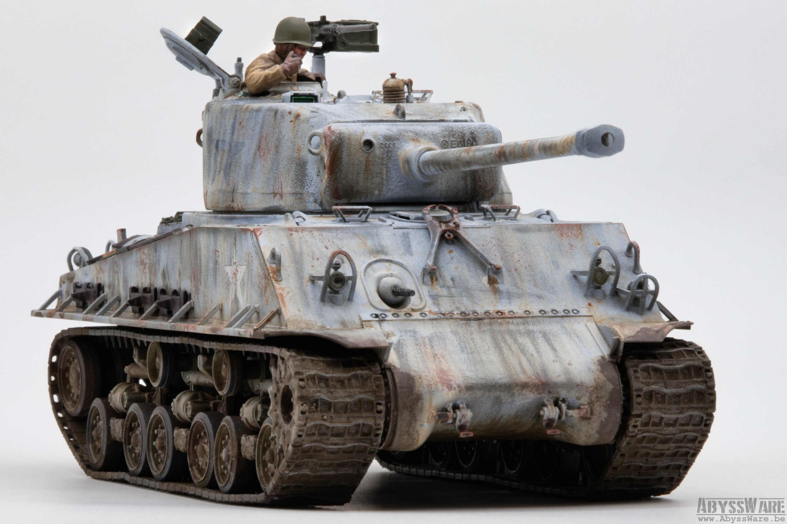 A detailed scale replica of a weathered military tank with a soldier figurine in the hatch, set against a plain white background.