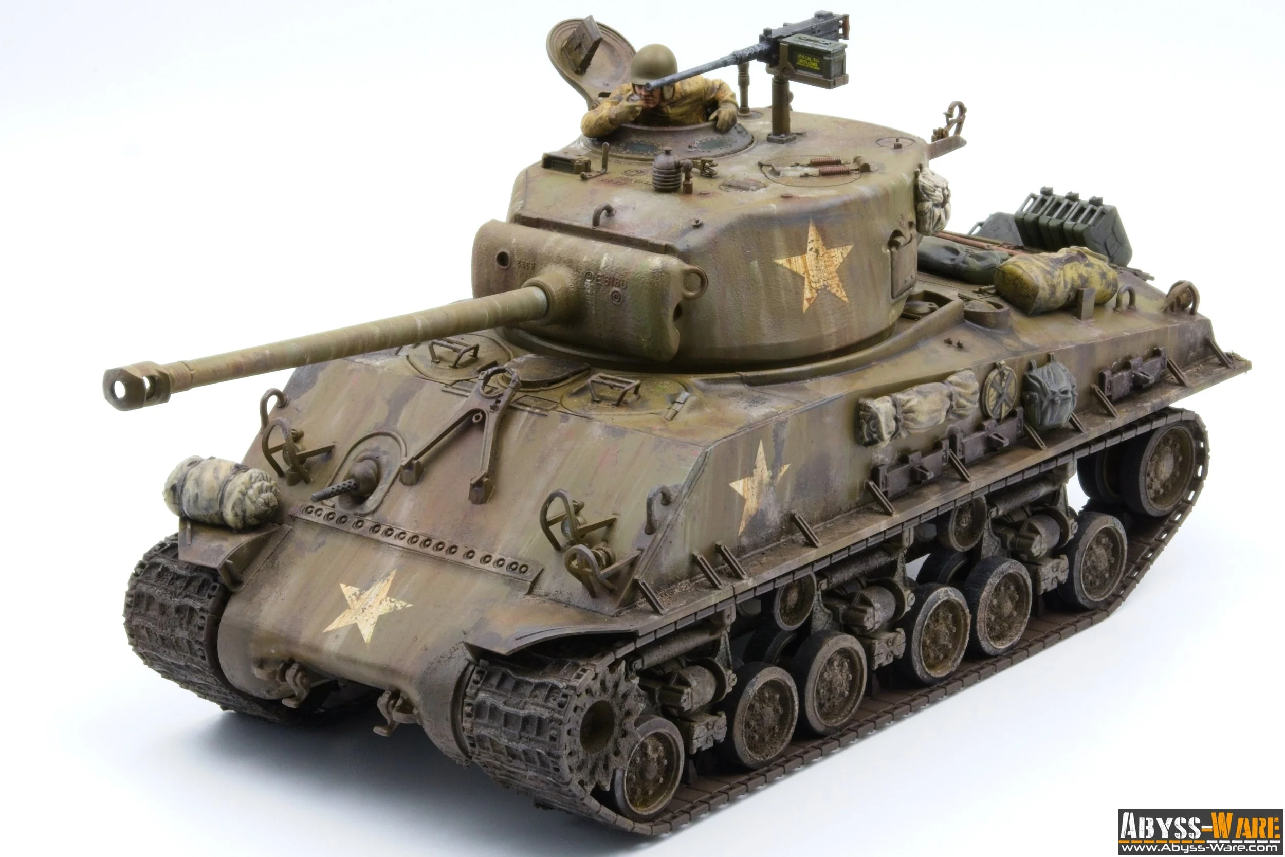 Model of a military tank with a soldier figure in the turret, decorated with weathered paint and military supplies, on a white background.