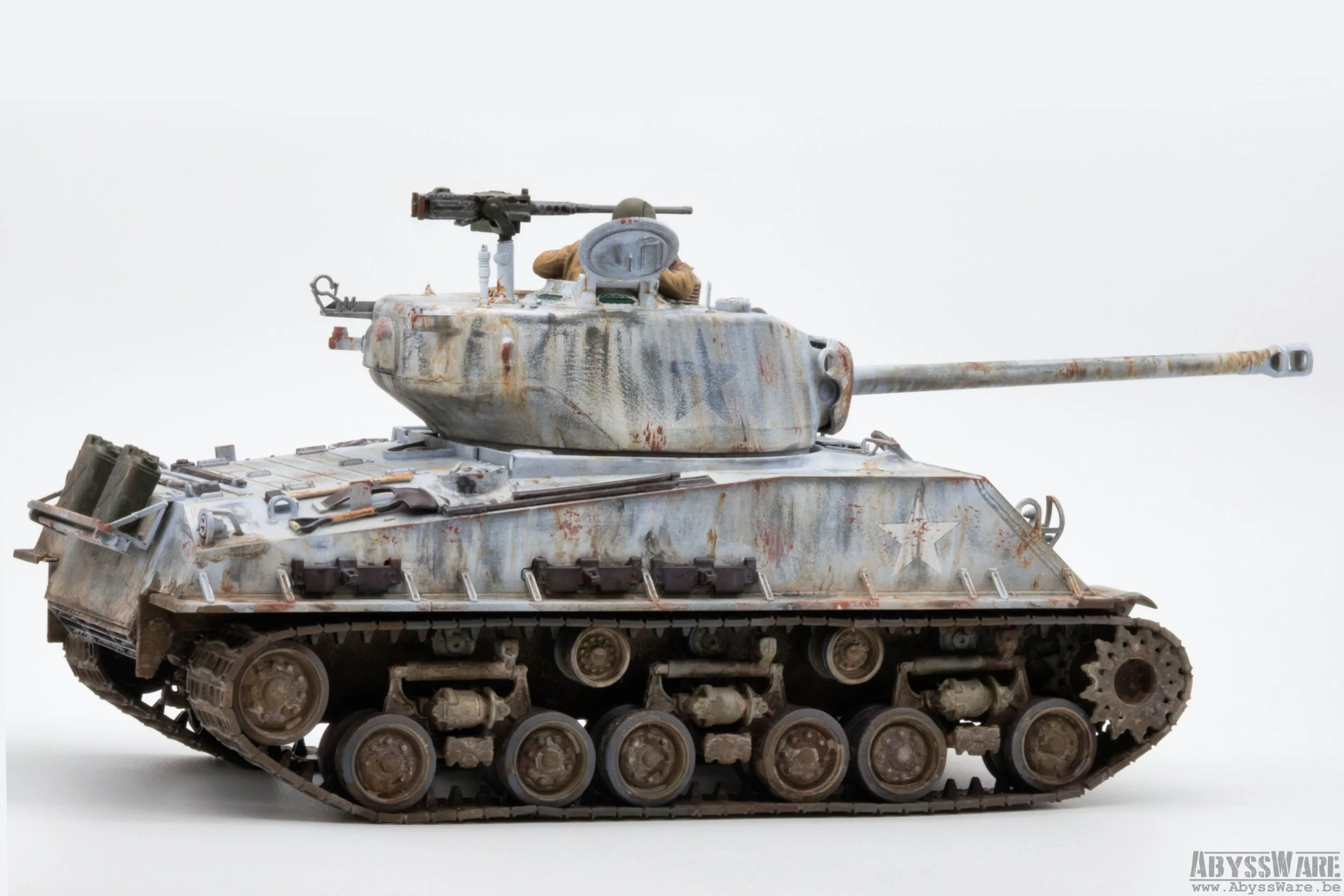 Model of a military tank with weathered, rusty paint, and a small plastic soldier figure in the turret's hatch, against a plain white background.