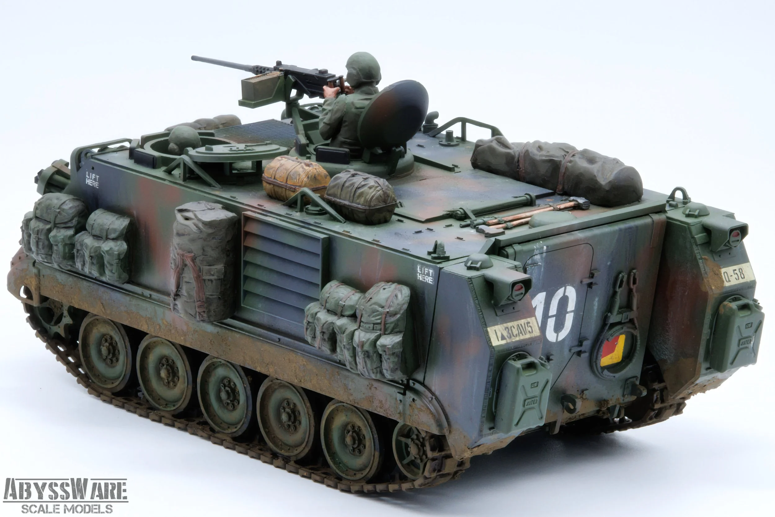 Scale model of a military armored vehicle with a soldier figure on top, equipped with a machine gun, based on a detailed and weathered military design.