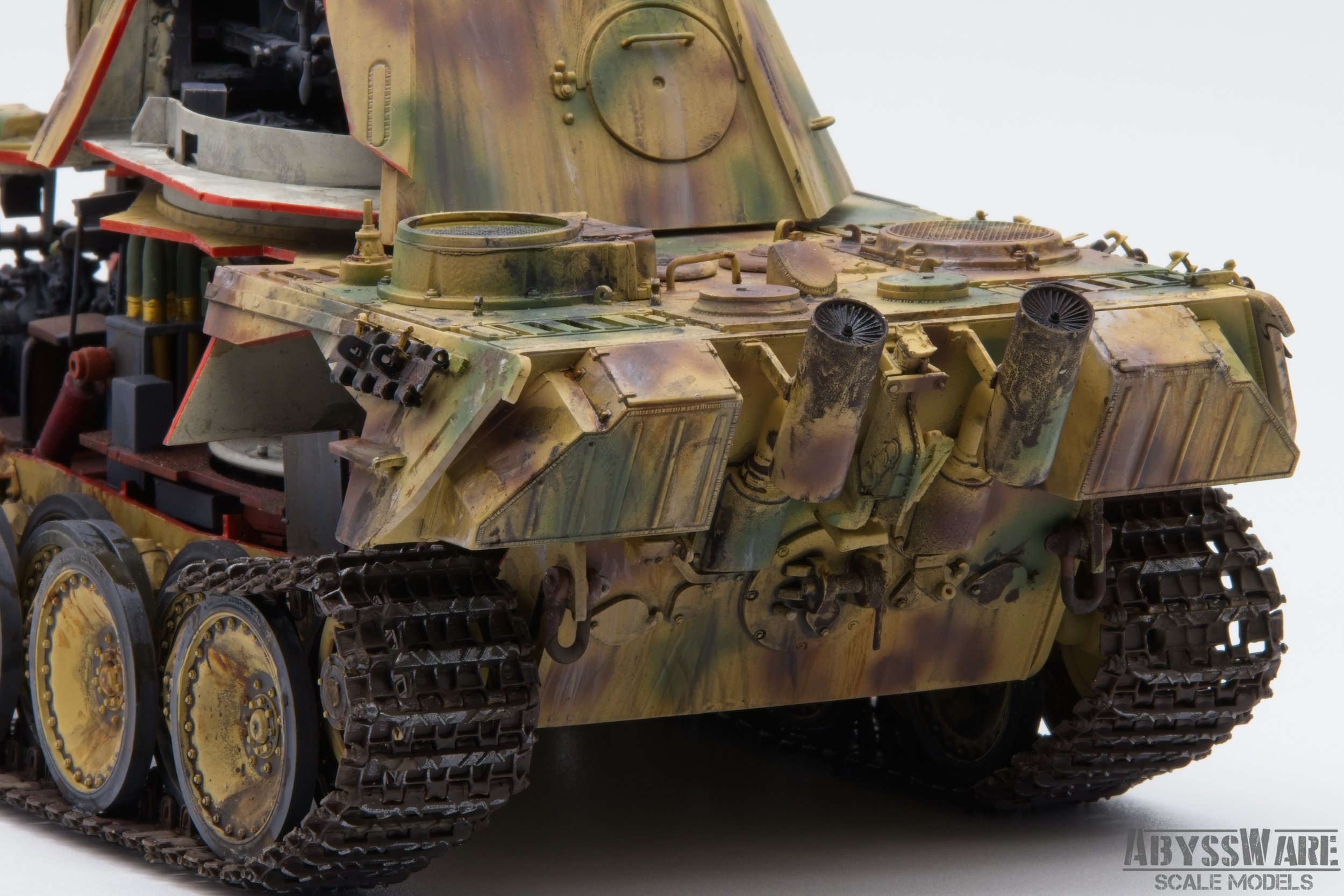 Close-up of a weathered, detailed scale model of a military tank with camouflage paint, tracks, and exhaust pipes visible.