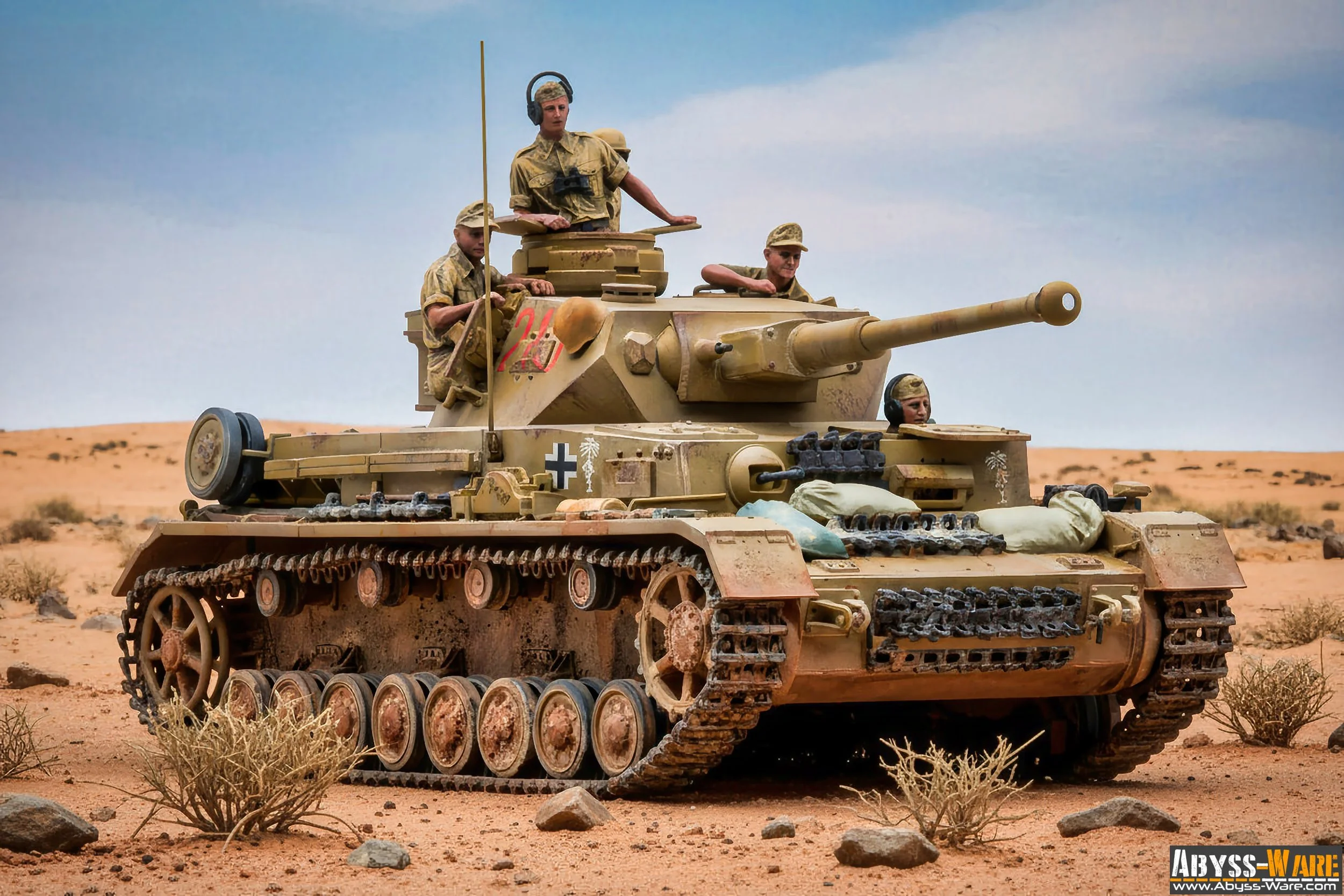 A military tank with four soldiers in desert terrain, the tank is tan with symbol markings, and the soldiers are wearing camouflage uniforms and helmets, some are inside the tank and others are on top.
