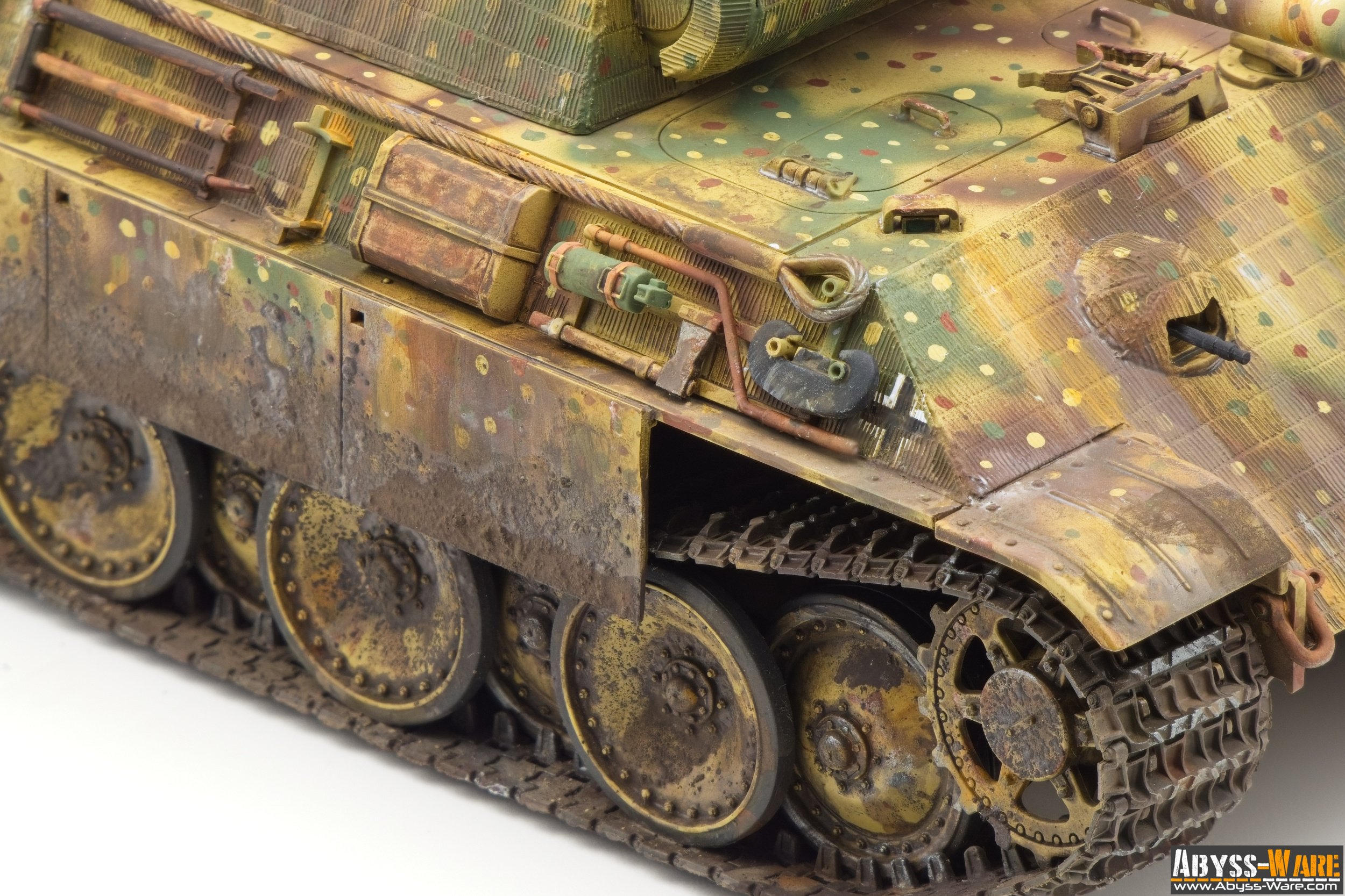 Close-up of a weathered tank model with camouflage paint, showing wheels, tracks, and detailed external components.