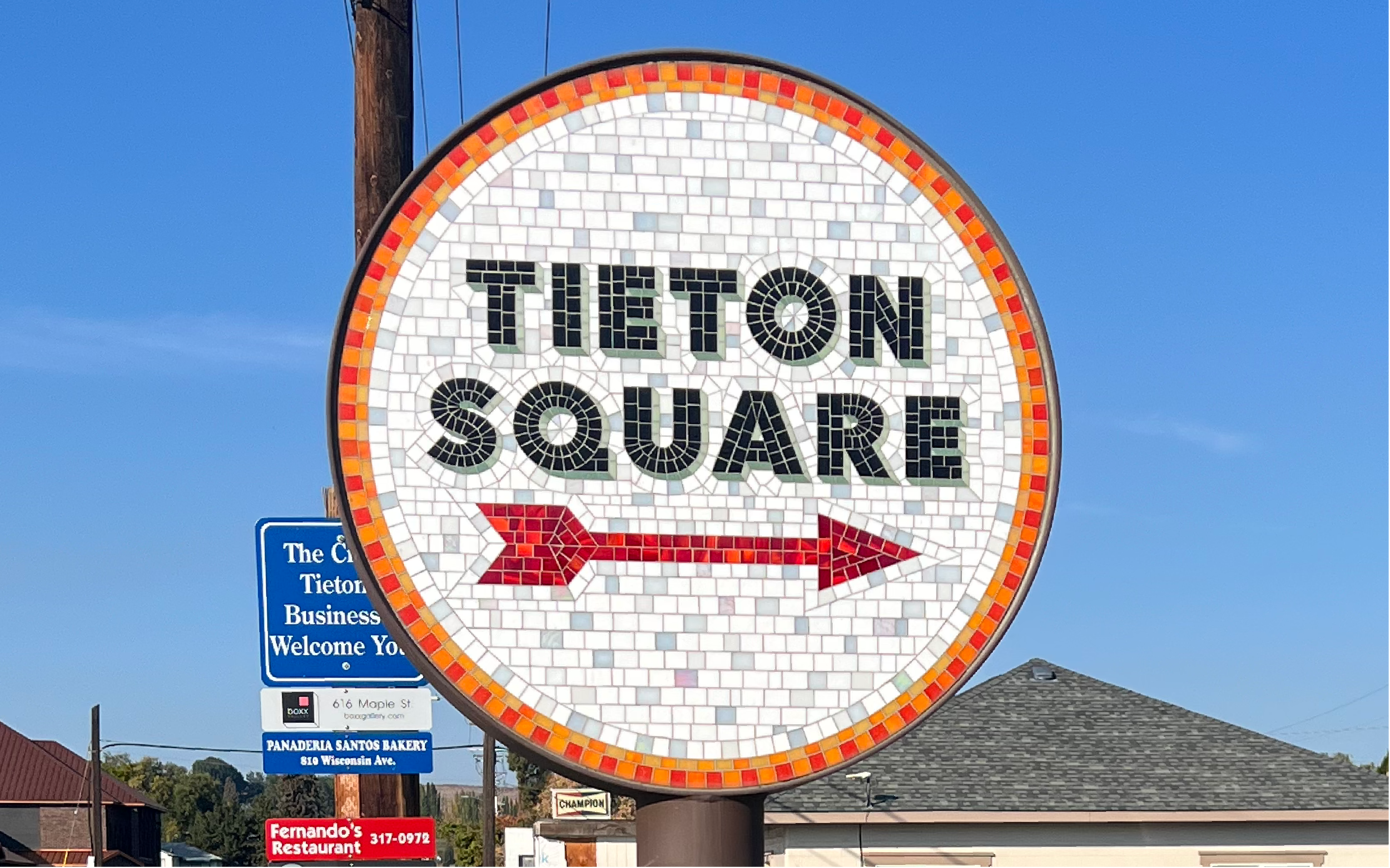 Mosaic sign made by Tieton Mosaic Co. for Tieton Square with a red arrow pointing to the right, set against a blue sky