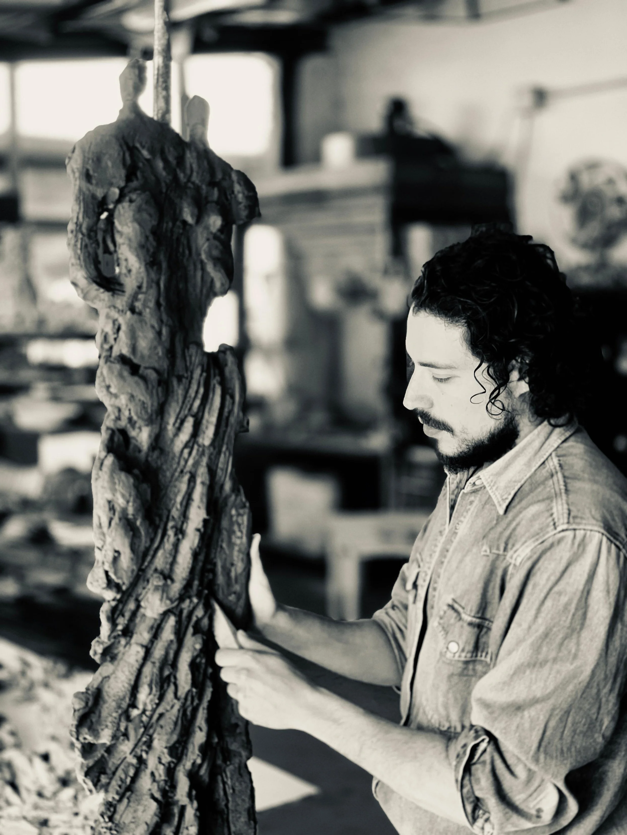 Artigiano che lavora su una scultura di legno in un laboratorio.