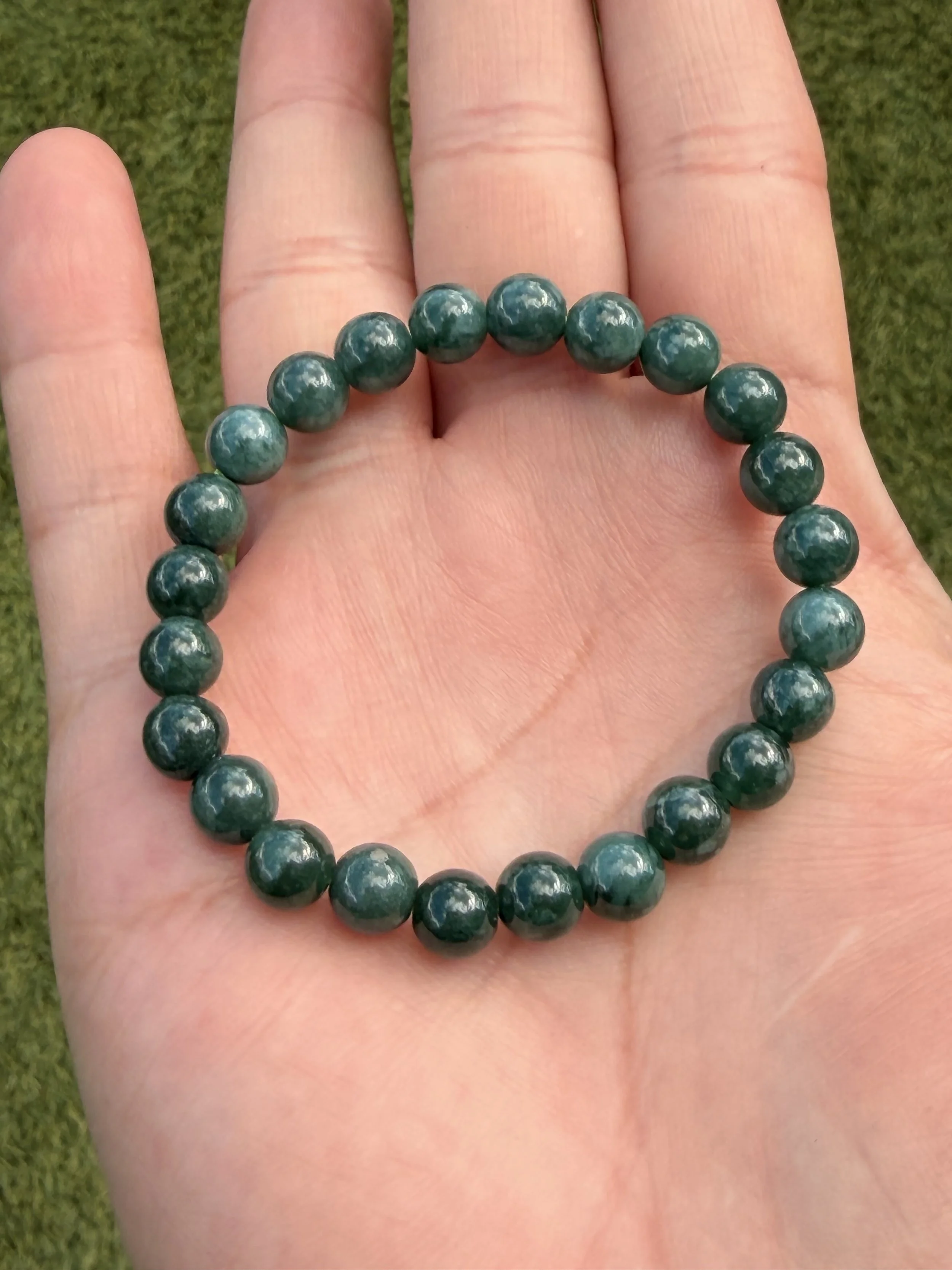 Dark Green Type A Jadeite Jade Stretch Bracelet being held by a hand